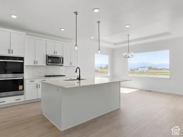 Kitchen featuring white cabinetry, an expansive central island with stone-finish countertops, stainless steel double wall ovens, recessed lighting, and wood-finish flooring