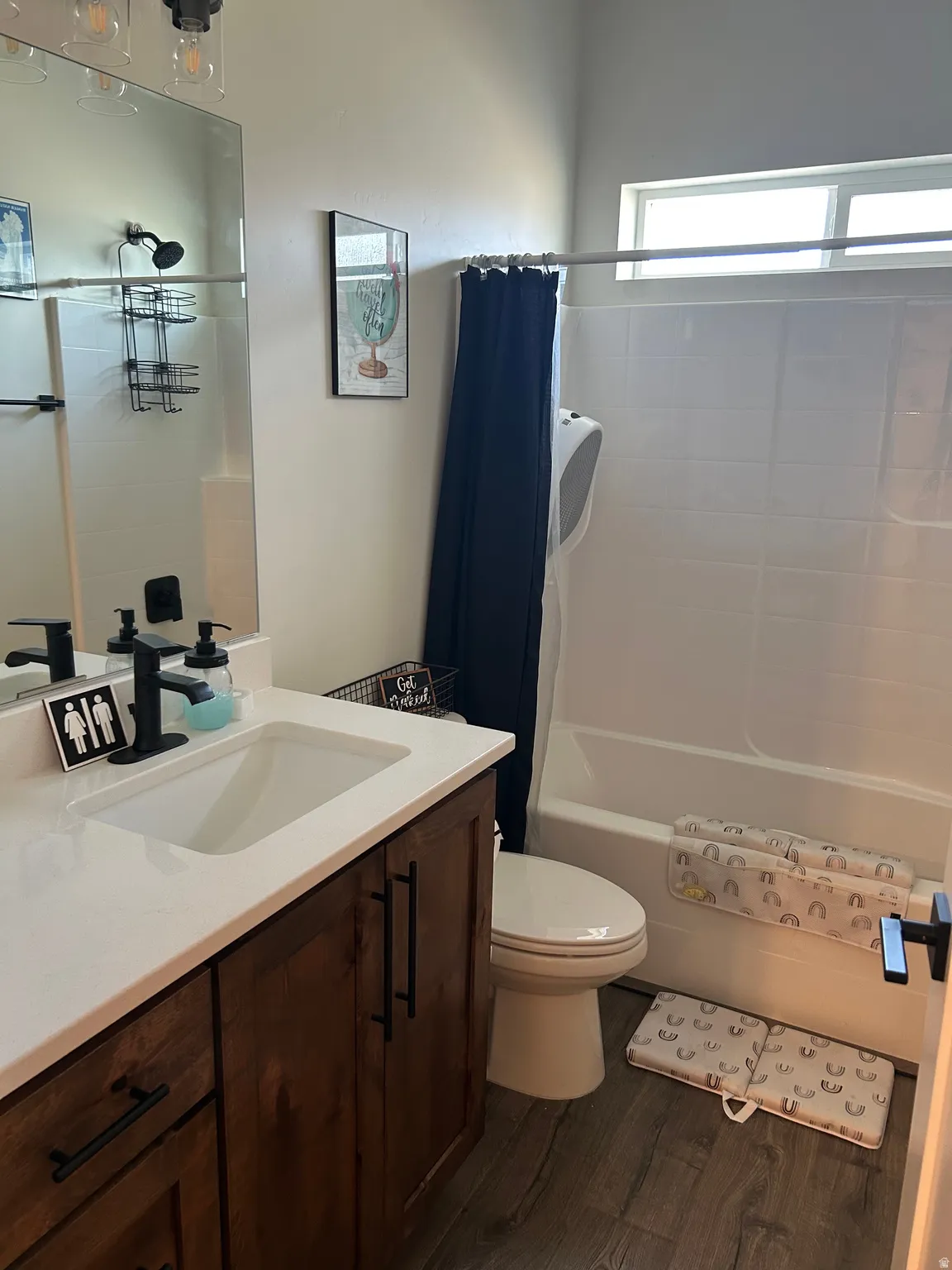 Bathroom featuring a wood-finish vanity with white countertop, integrated sink, and matte black fixtures