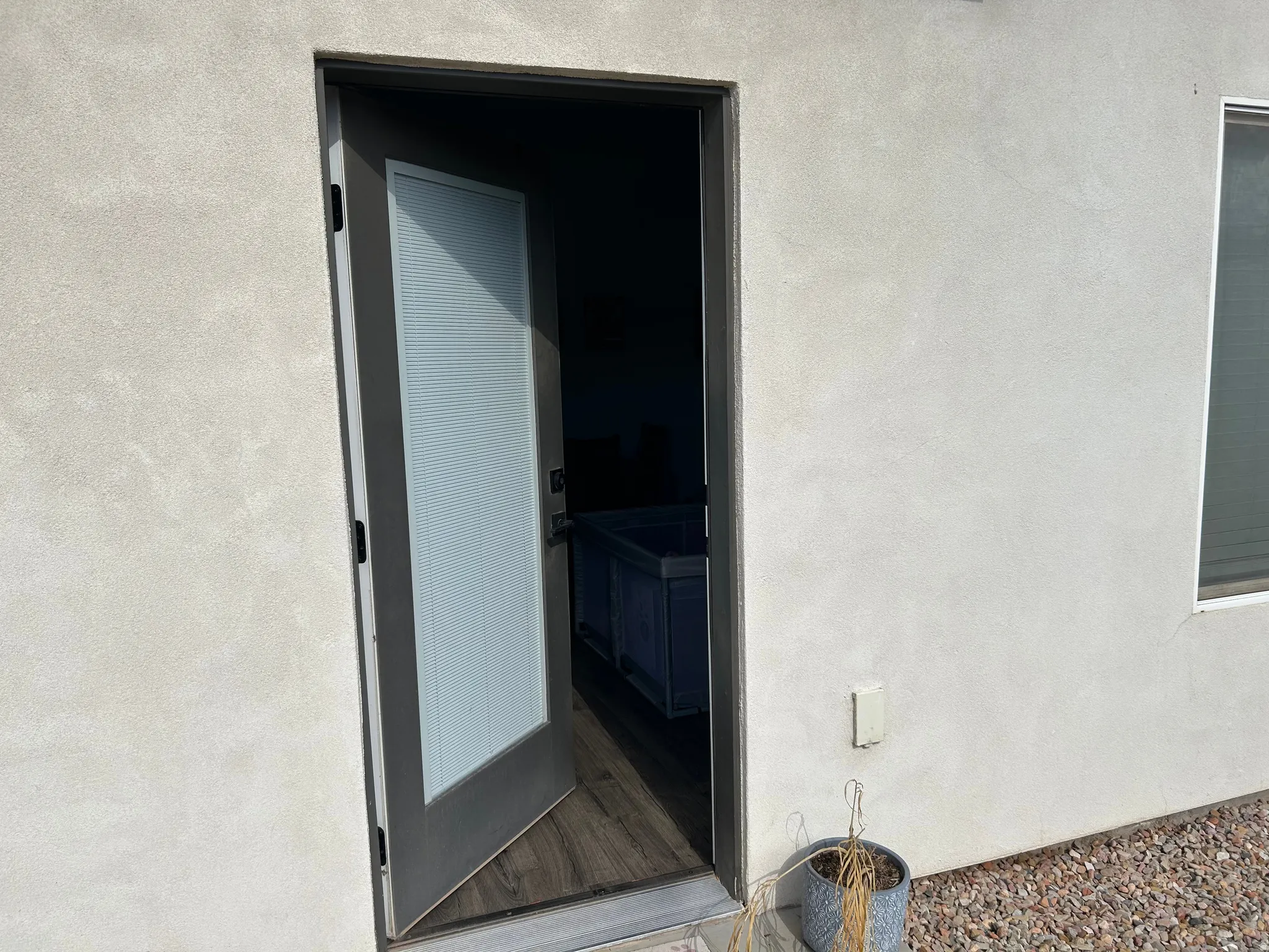 Exterior stucco finish with a window and a glass-paneled entry door