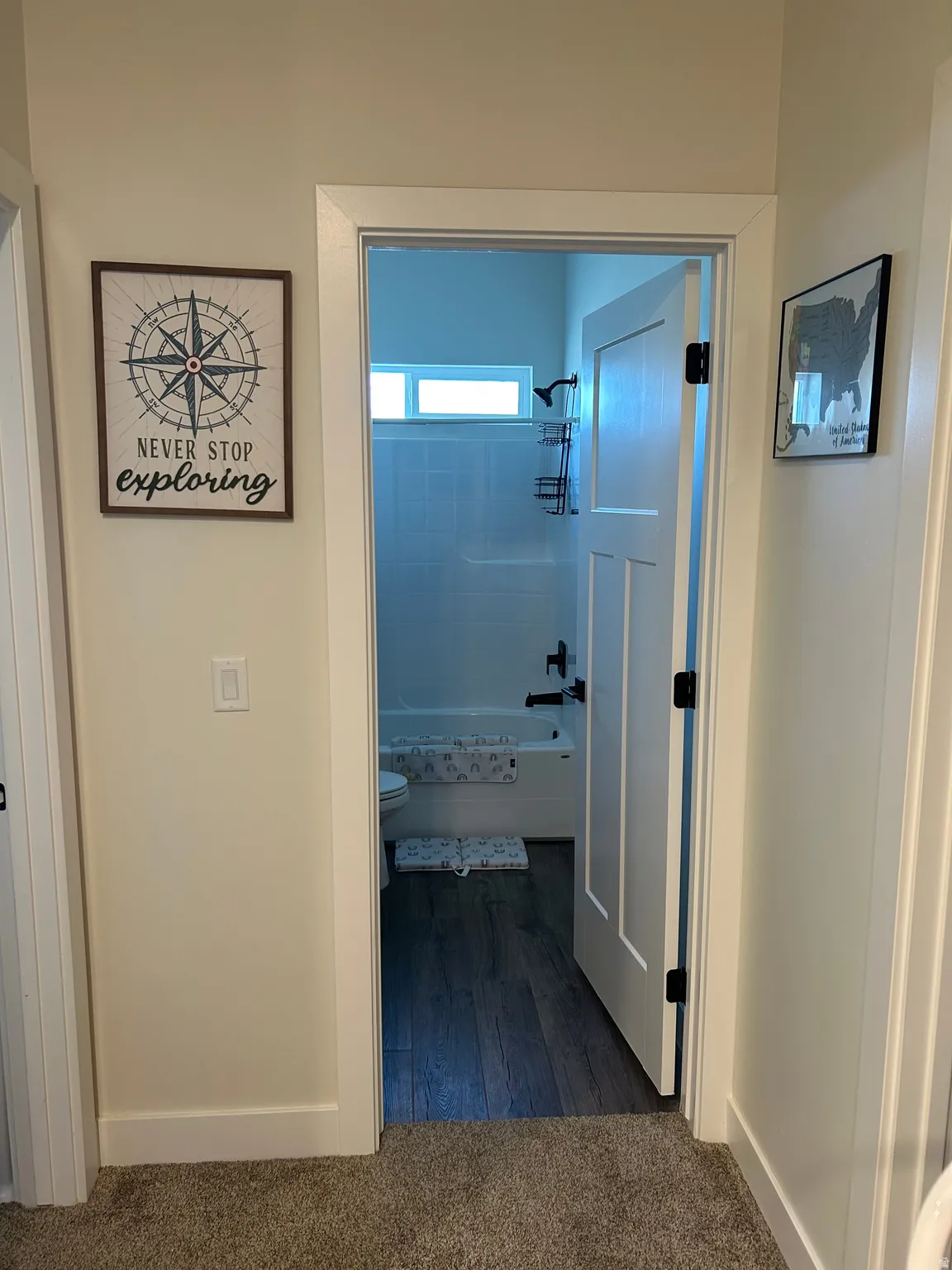 Bathroom featuring wood-finish flooring, white subway tile shower surround, a white bathtub, and black fixtures