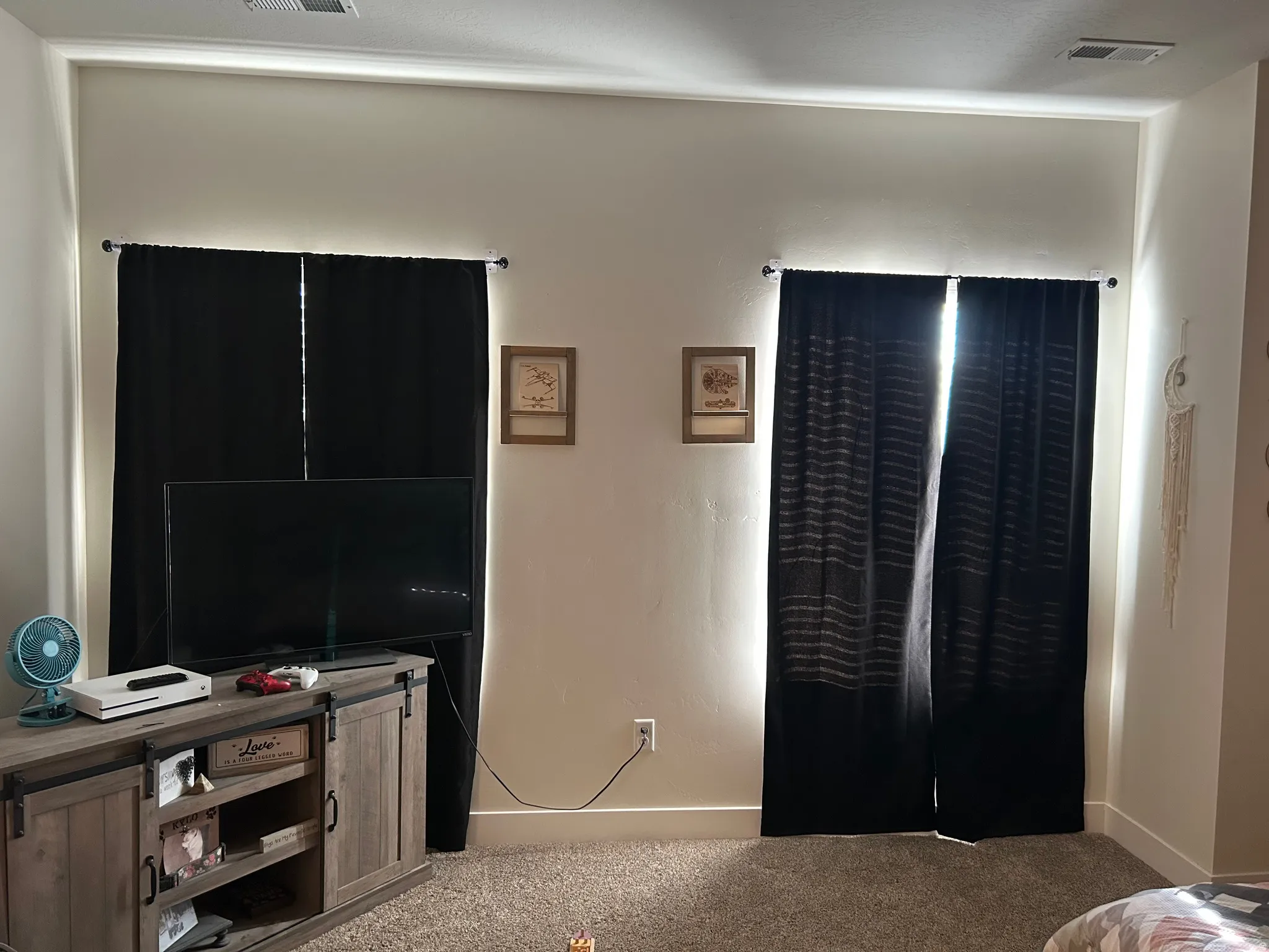 Carpeted interior space with two windows featuring dark drapery panels