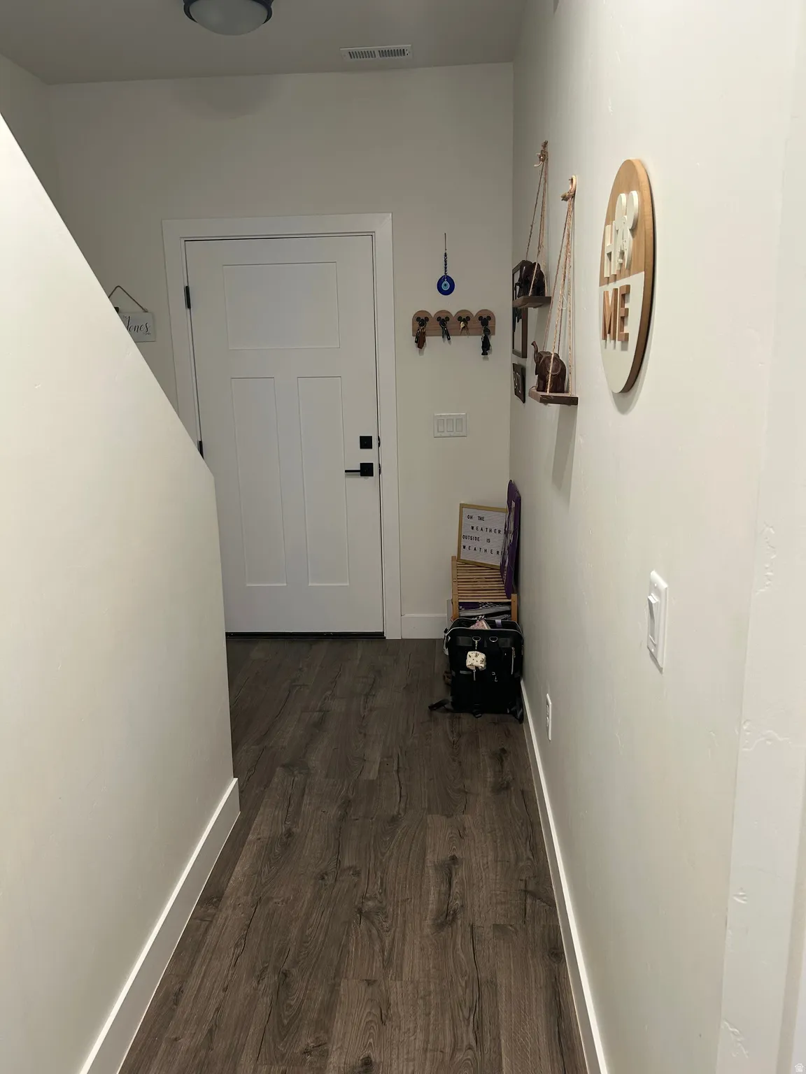 Entryway featuring wood-finish flooring, a white paneled door with black hardware, and a semi-flush mount ceiling light