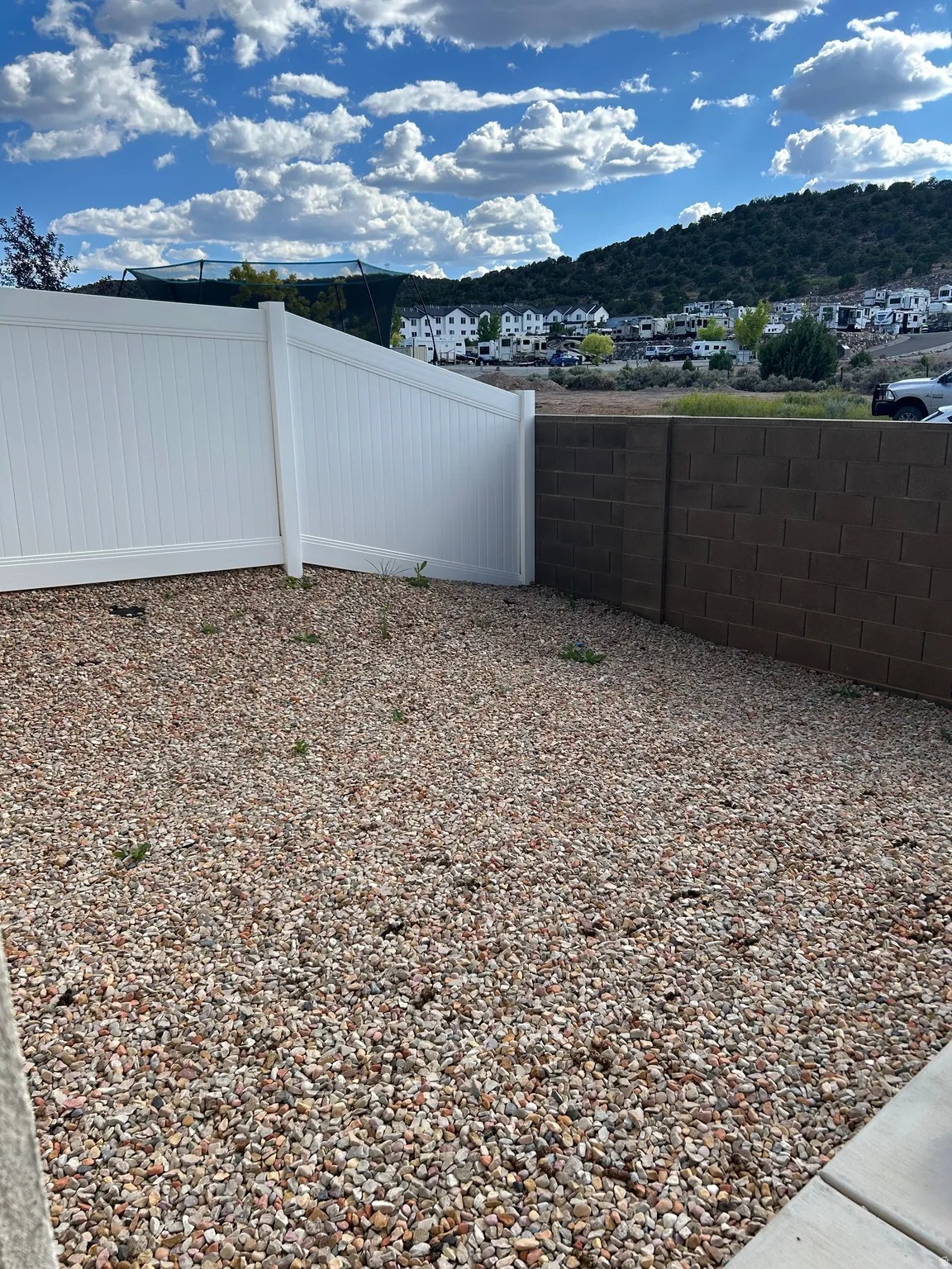 Backyard featuring gravel landscaping, a white vinyl fence, and a block wall