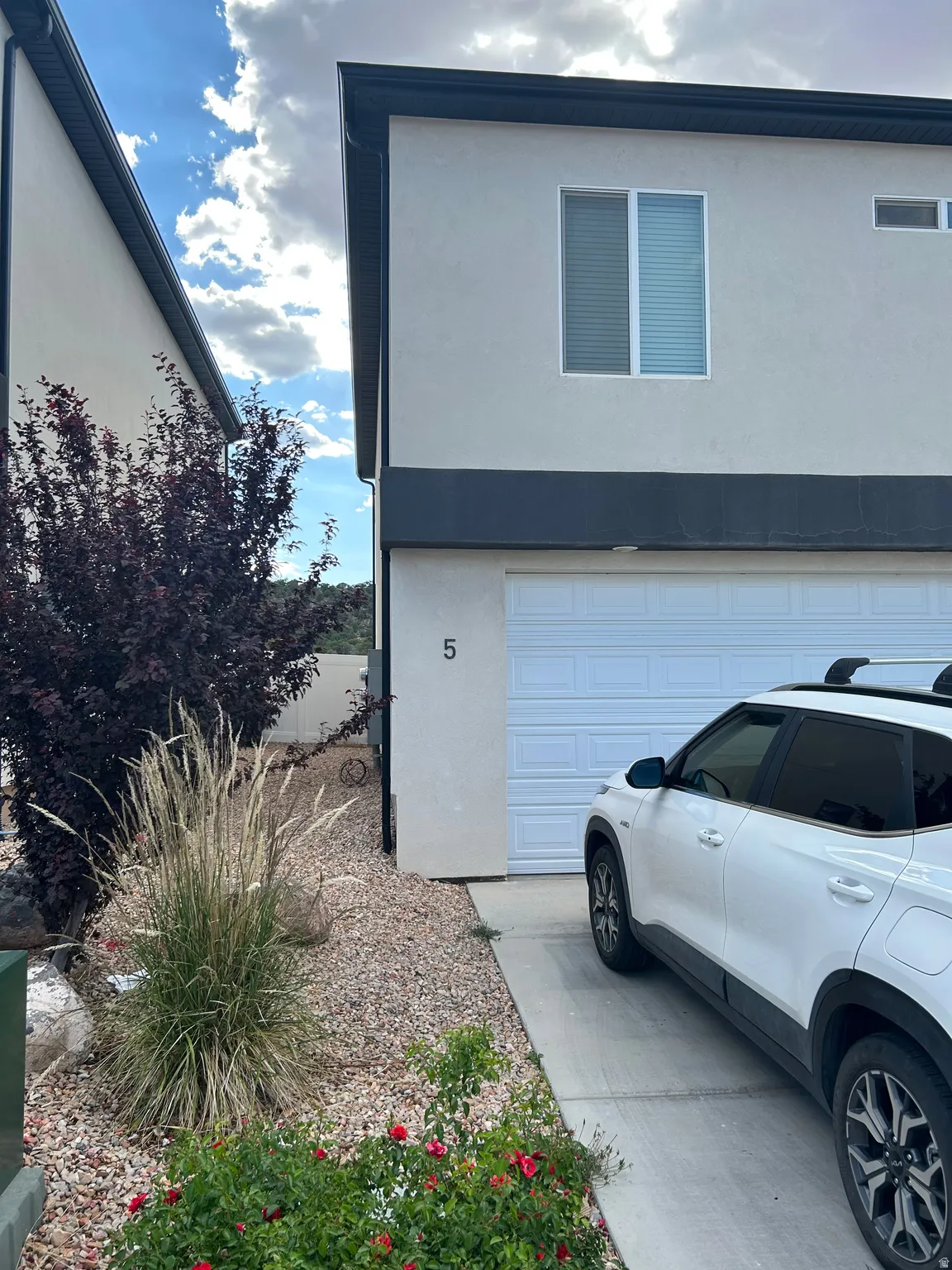 Contemporary stucco exterior with dark trim and a white garage door