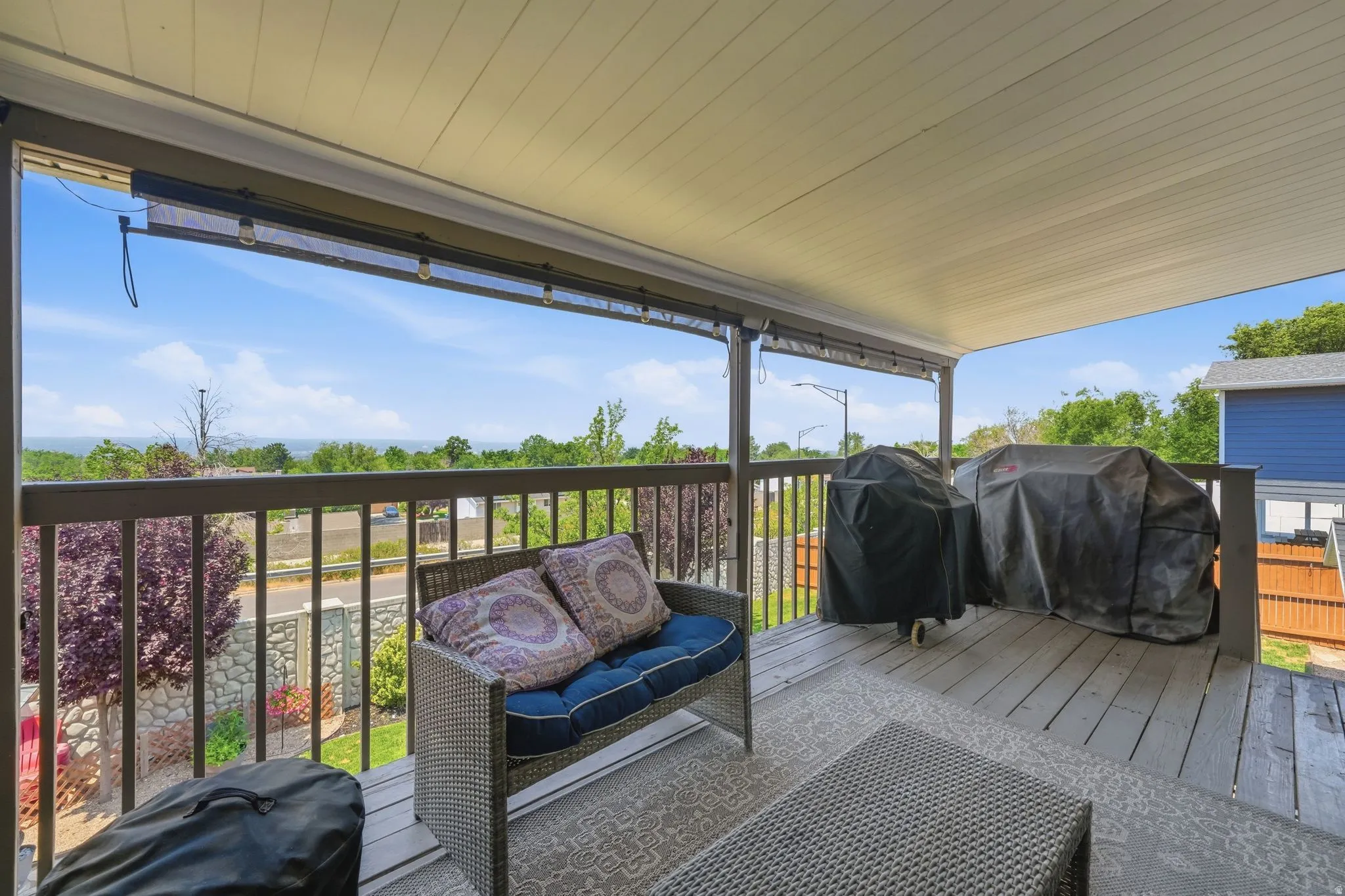 Spacious covered deck featuring composite decking and metal railings, overlooking distant scenery