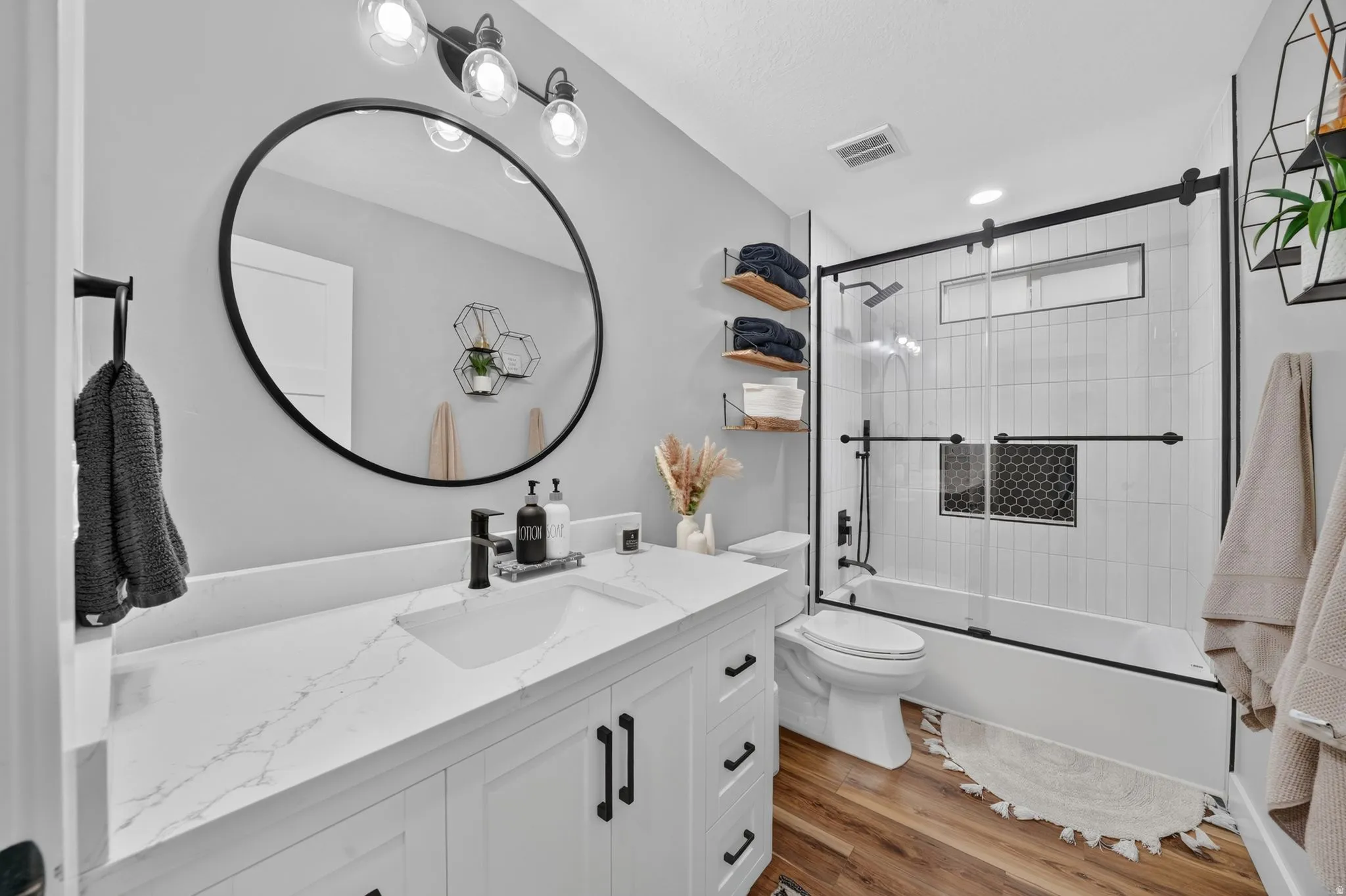 Bathroom featuring a white vanity with a white countertop, an undermount sink, and black hardware