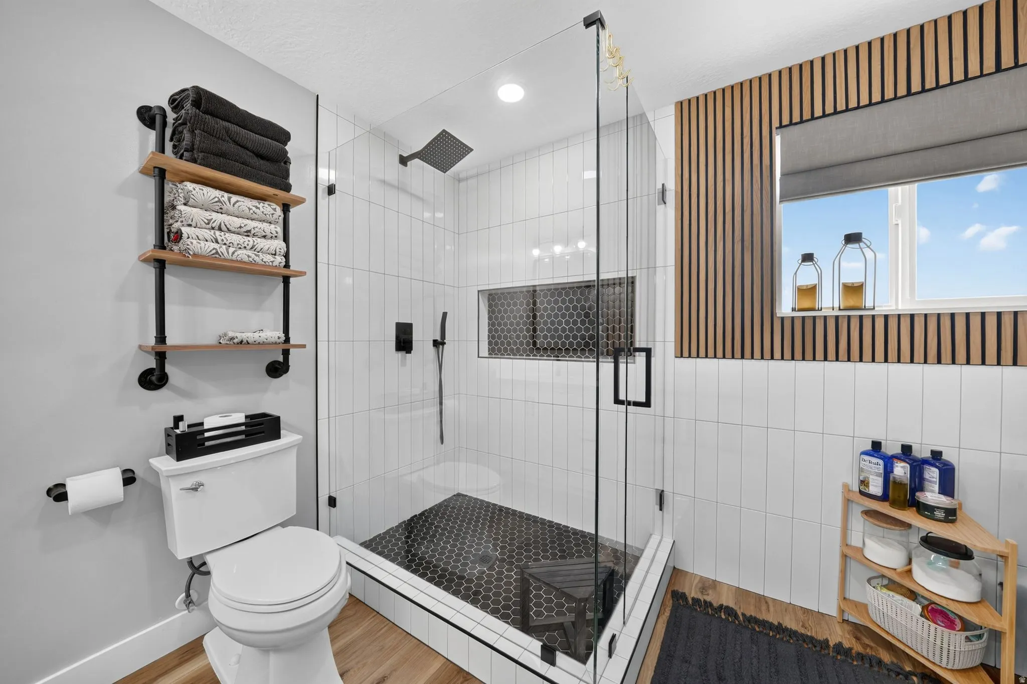 Contemporary bathroom featuring a spacious glass-enclosed shower with black hexagonal tile flooring and white vertical subway tile walls