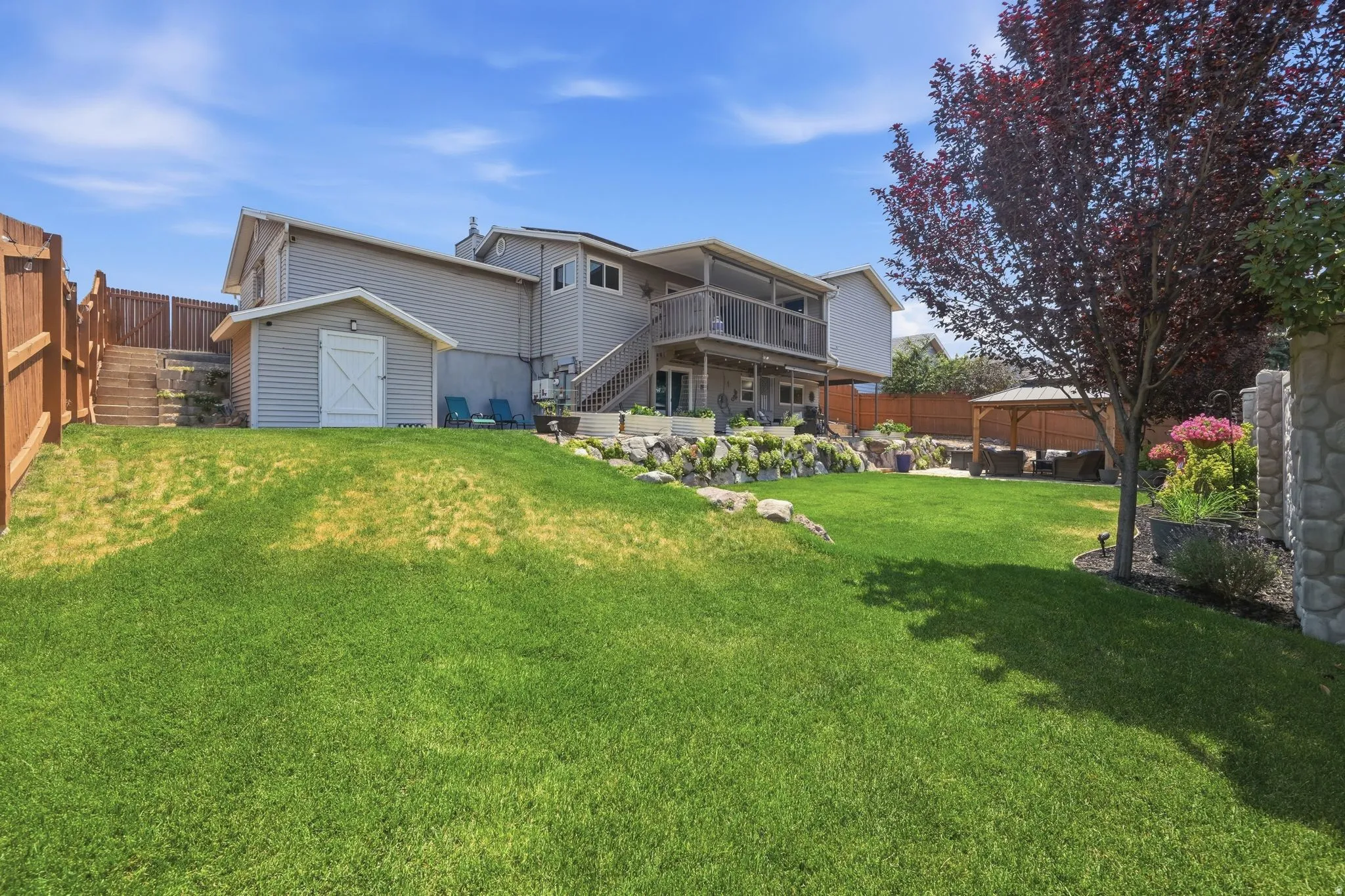 Expansive green lawn with a gray siding multi-level residence