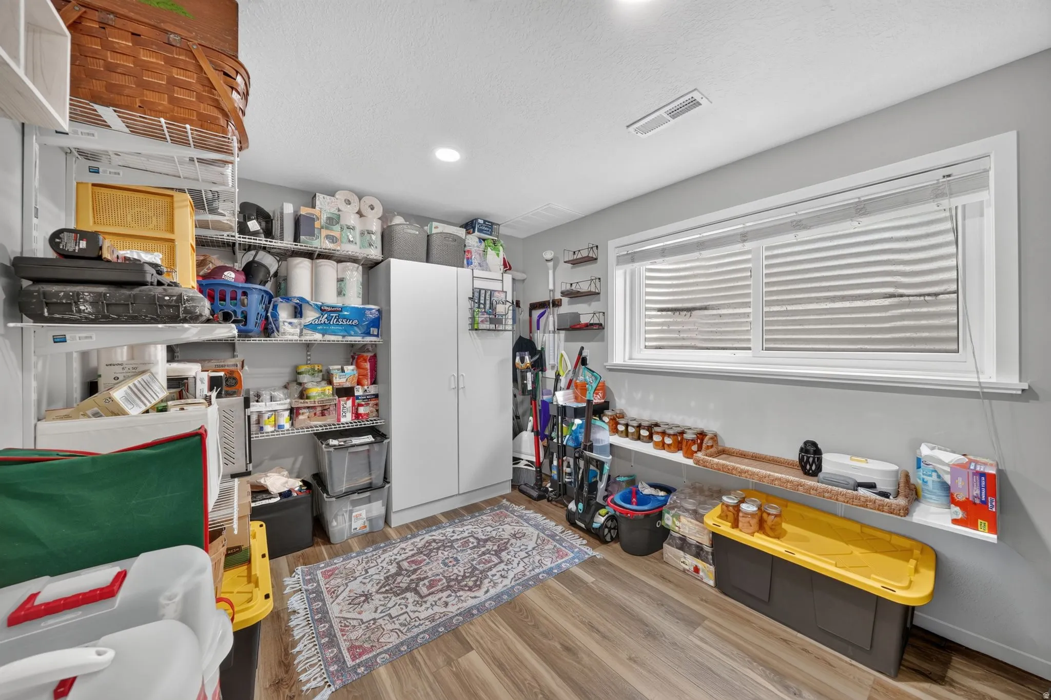 Storage room featuring wood-finish flooring, recessed lighting, and a horizontal window