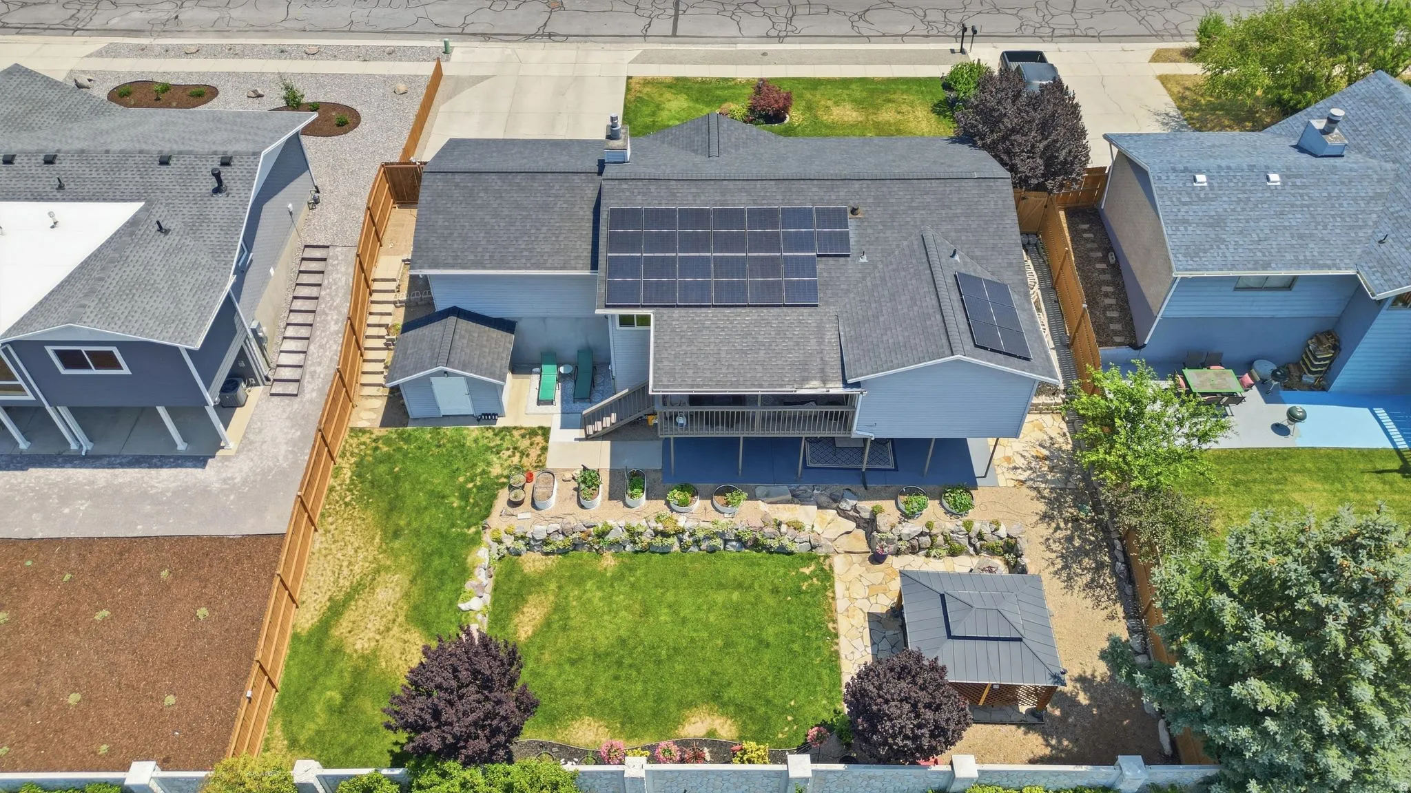 Rear exterior featuring a multi-level deck, expansive lawn, and rock garden landscaping