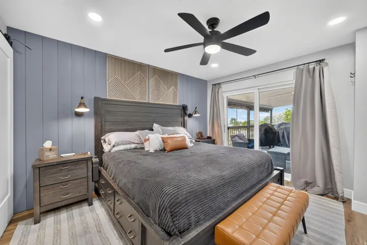 Spacious room featuring a blue accent wall with vertical paneling, recessed lighting, and a ceiling fan