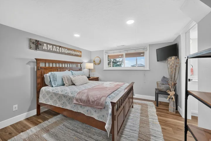 Bedroom with wood-finish flooring, recessed lighting, and a window with blinds