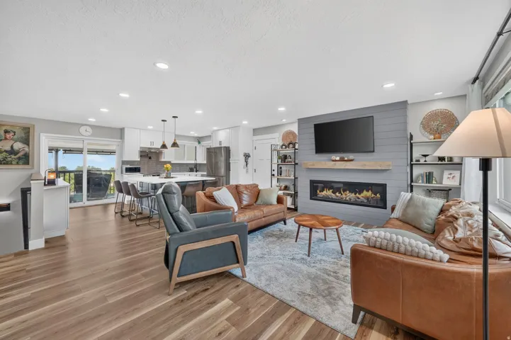 Open-concept living space featuring wood-finish flooring, recessed lighting, and a modern fireplace with a shiplap accent wall