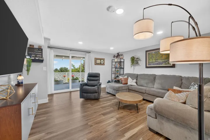 Spacious living area featuring wood-finish flooring, recessed lighting, and a sliding glass door providing natural light and exterior access