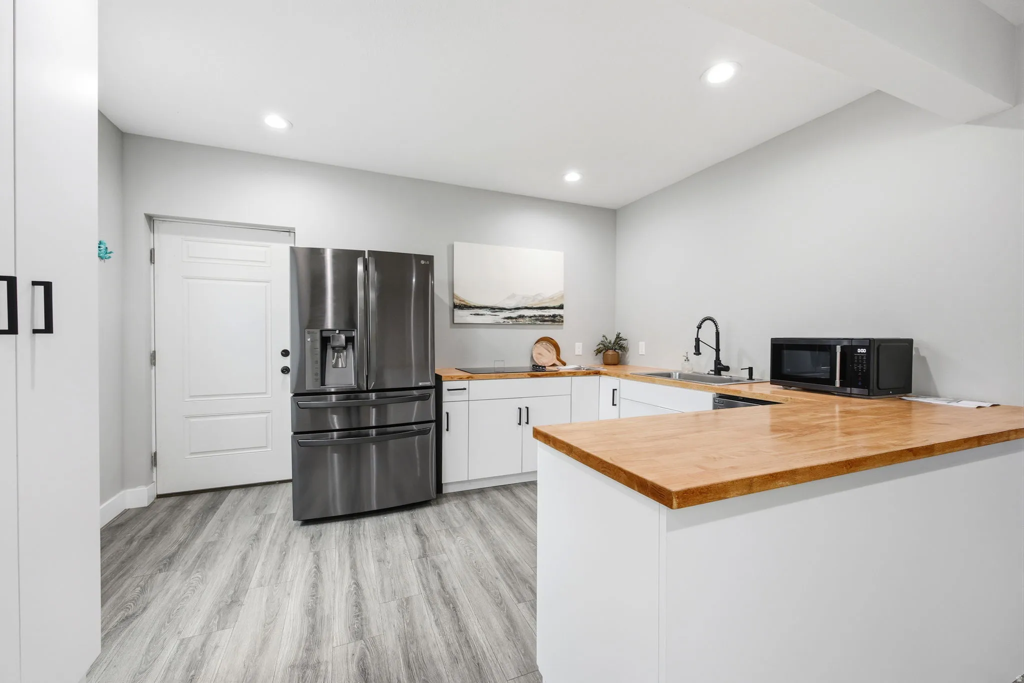 Kitchen featuring wood-finish countertops, white cabinetry with matte black hardware, and stainless steel appliances