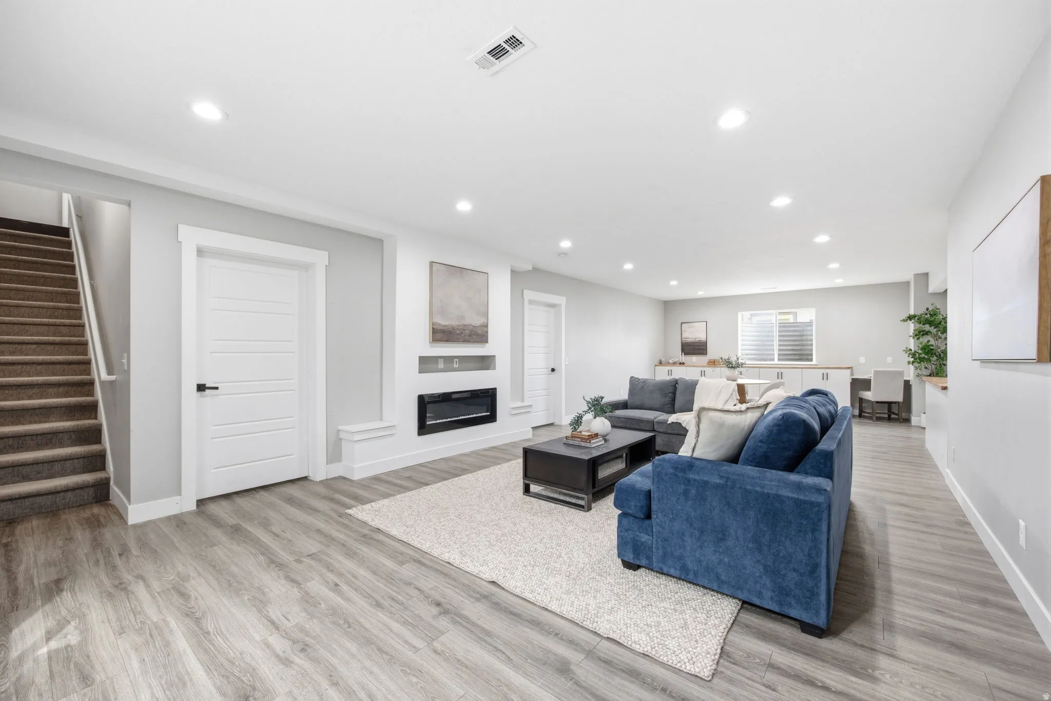 Spacious lower-level living area featuring wood-finish flooring, recessed lighting, and a built-in electric fireplace