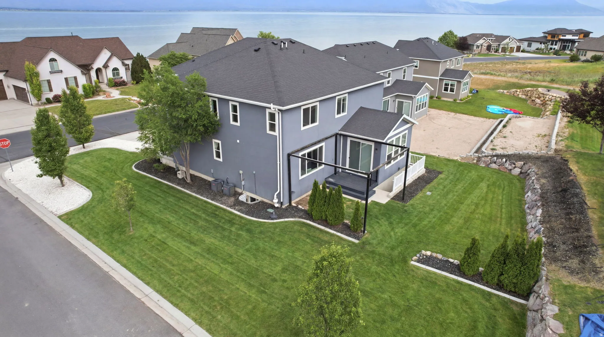 Expansive green lawn surrounds this two-story residence with dark grey siding and a black shingle roof