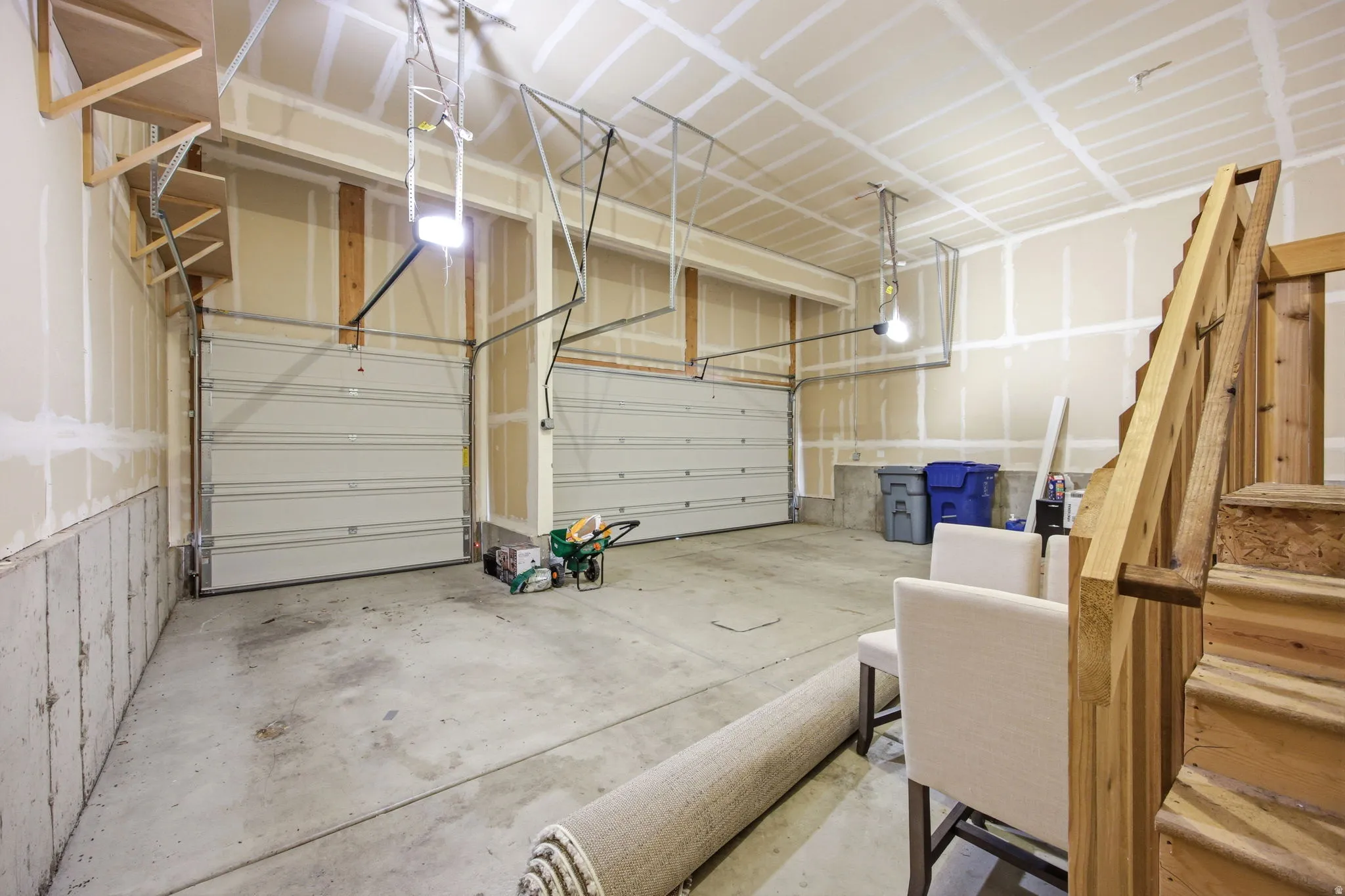 Spacious garage featuring two overhead doors, concrete flooring, and bare drywall walls