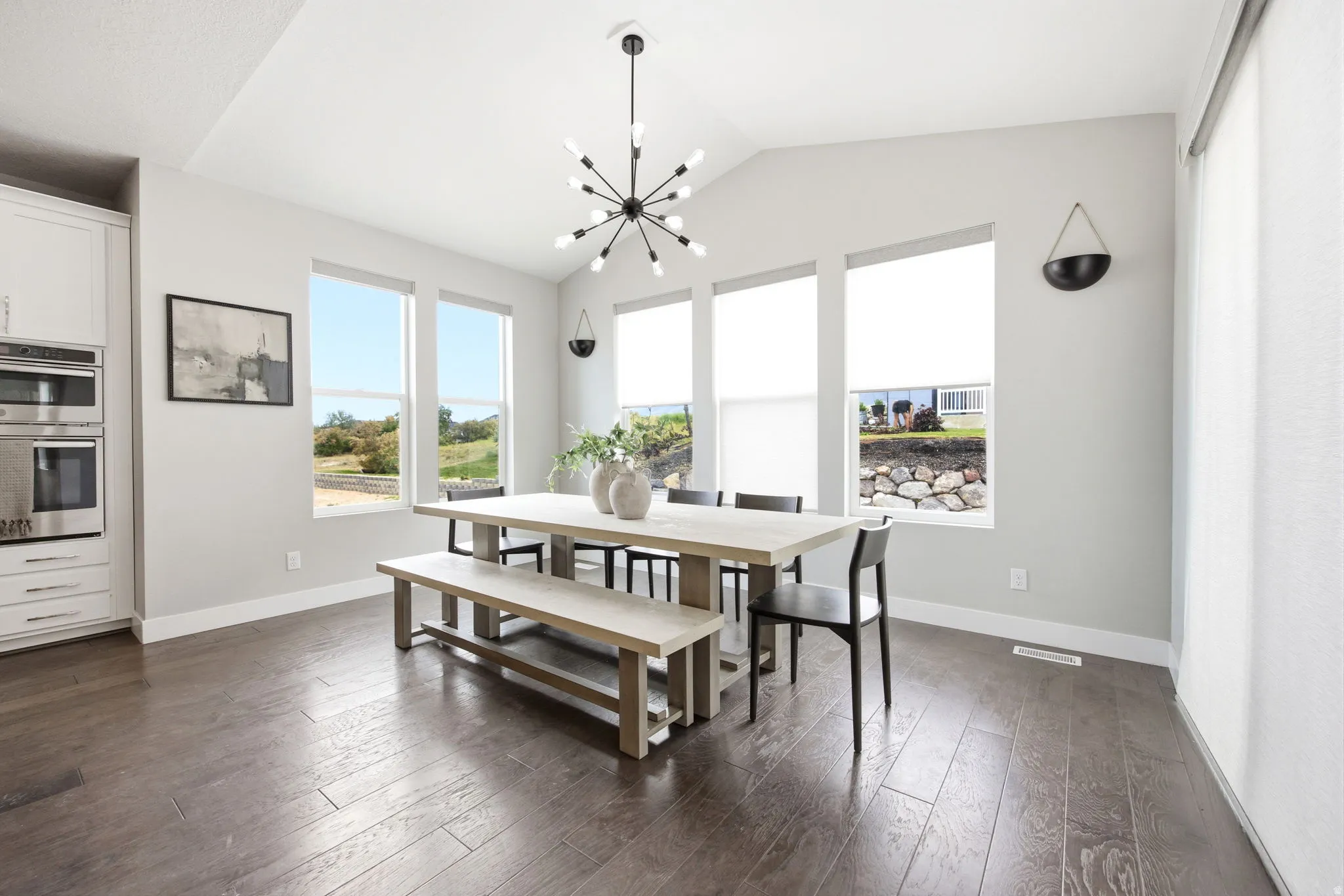 Bright dining area featuring a vaulted ceiling and a modern chandelier