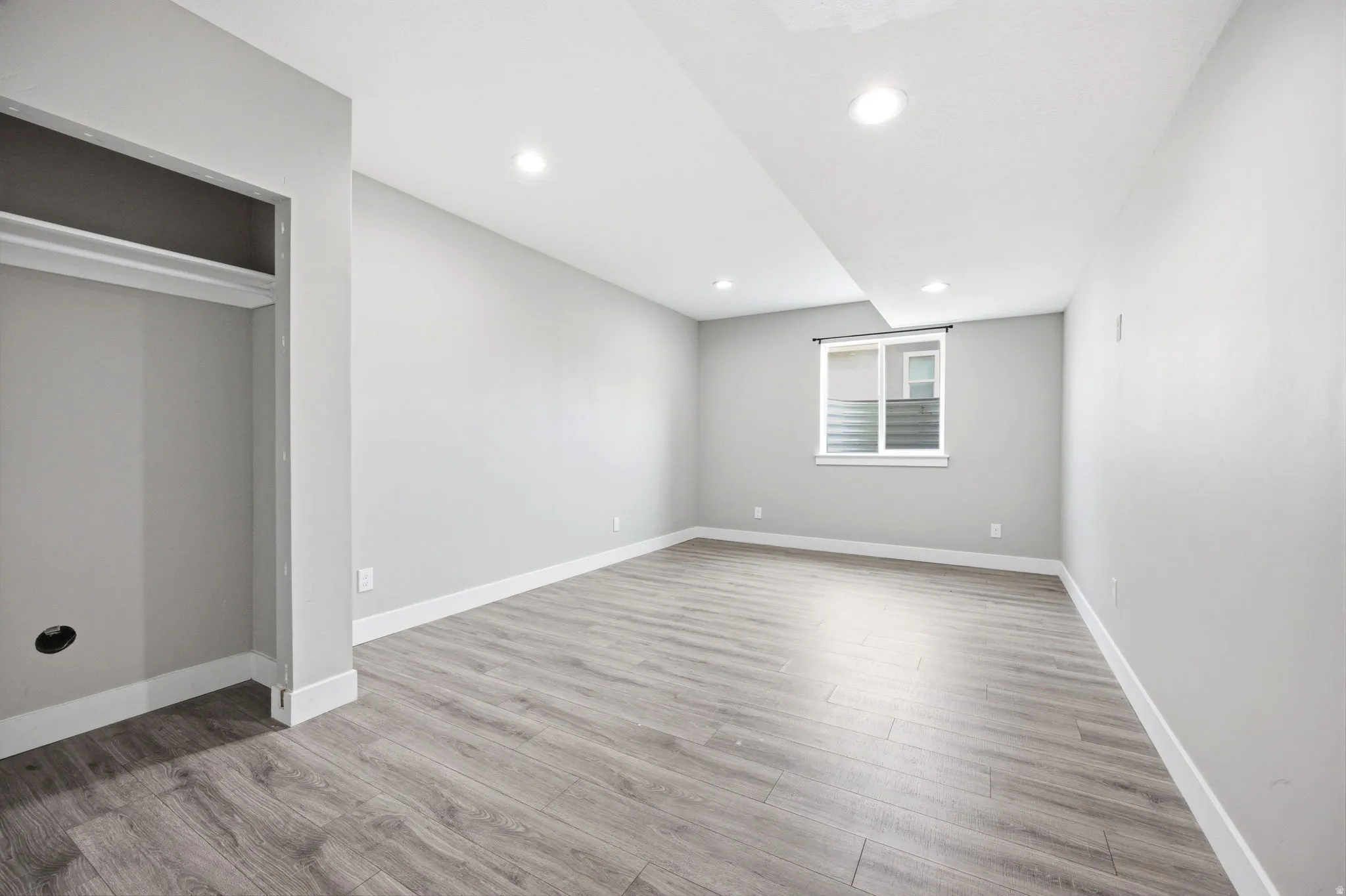 Spacious room featuring wood-finish flooring, recessed lighting, and a neutral wall palette