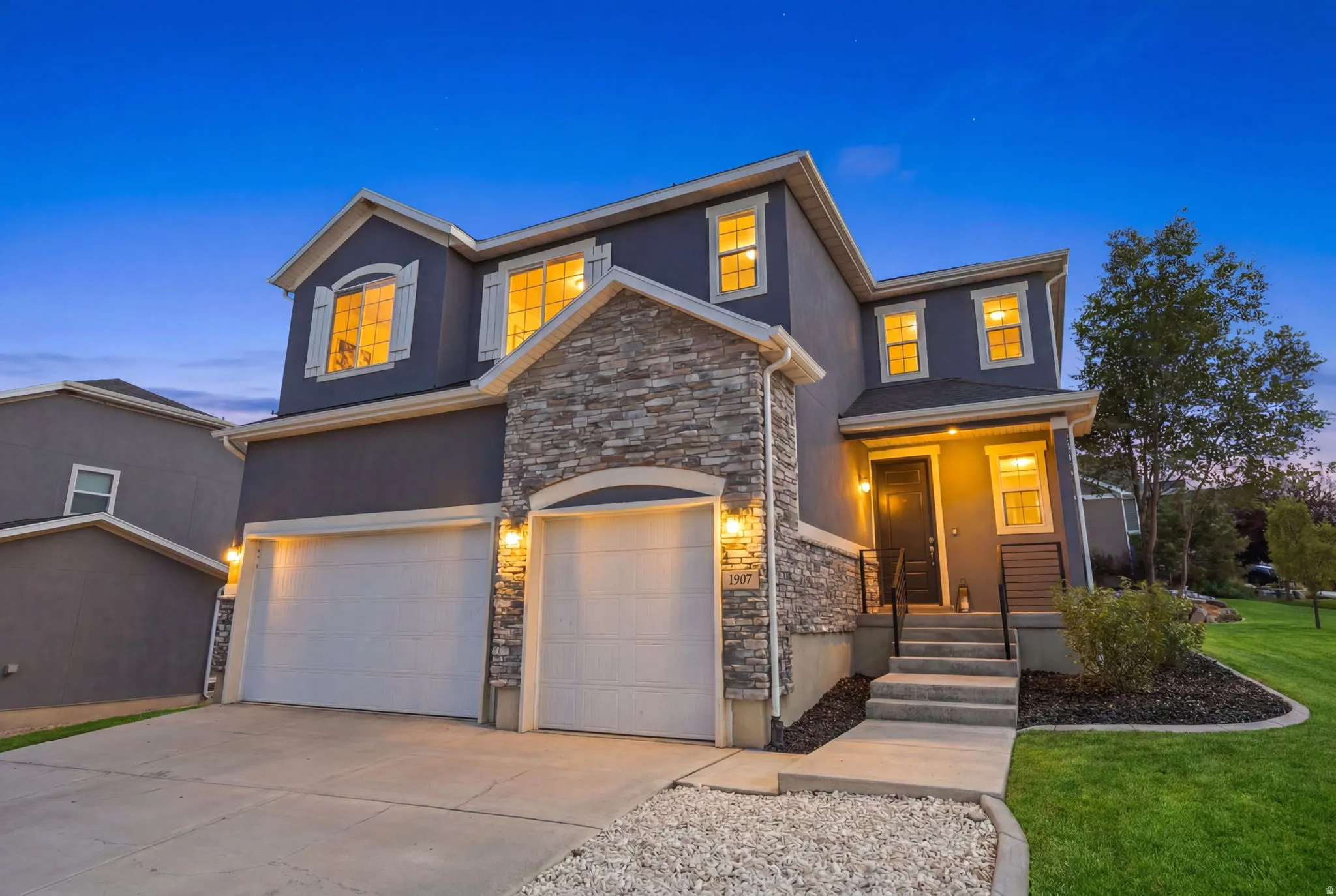 Two-story stucco exterior featuring stone accents and a dual garage