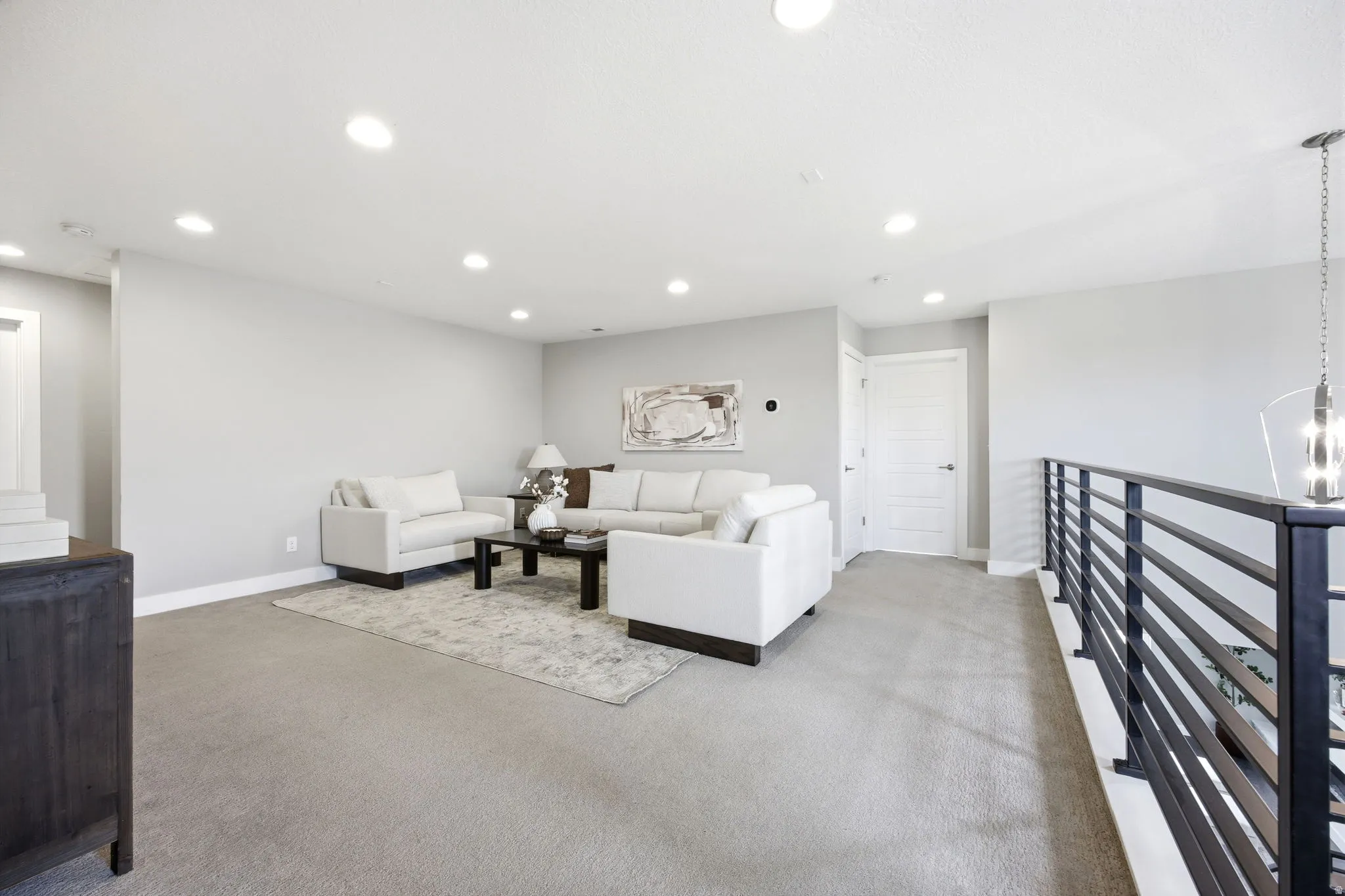 Versatile loft space featuring plush carpeting, recessed lighting, and a modern black horizontal railing