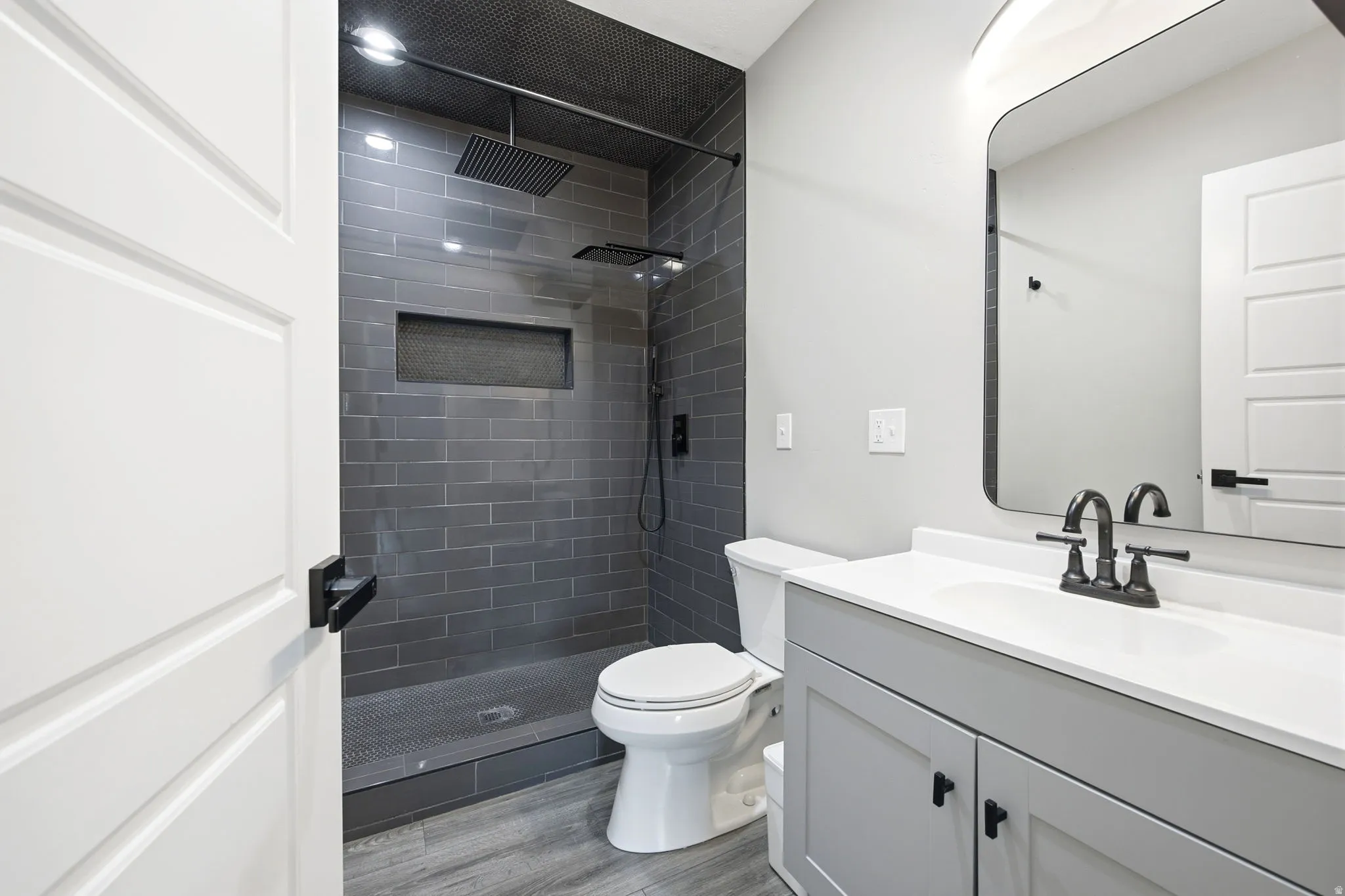 Bathroom featuring a walk-in shower with charcoal subway tile and a built-in niche, dual shower heads, and matte black fixtures