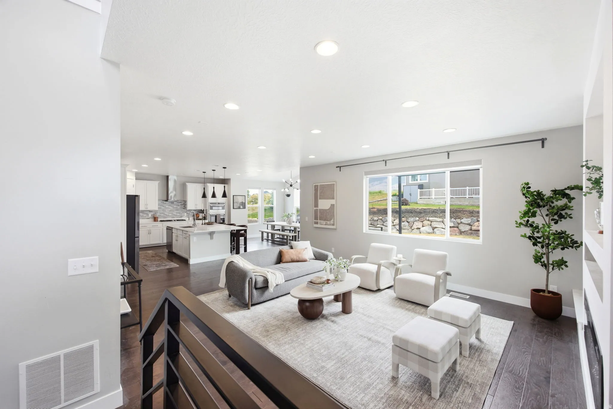 Open-concept living area featuring dark wood-finish flooring, recessed lighting, and a large window