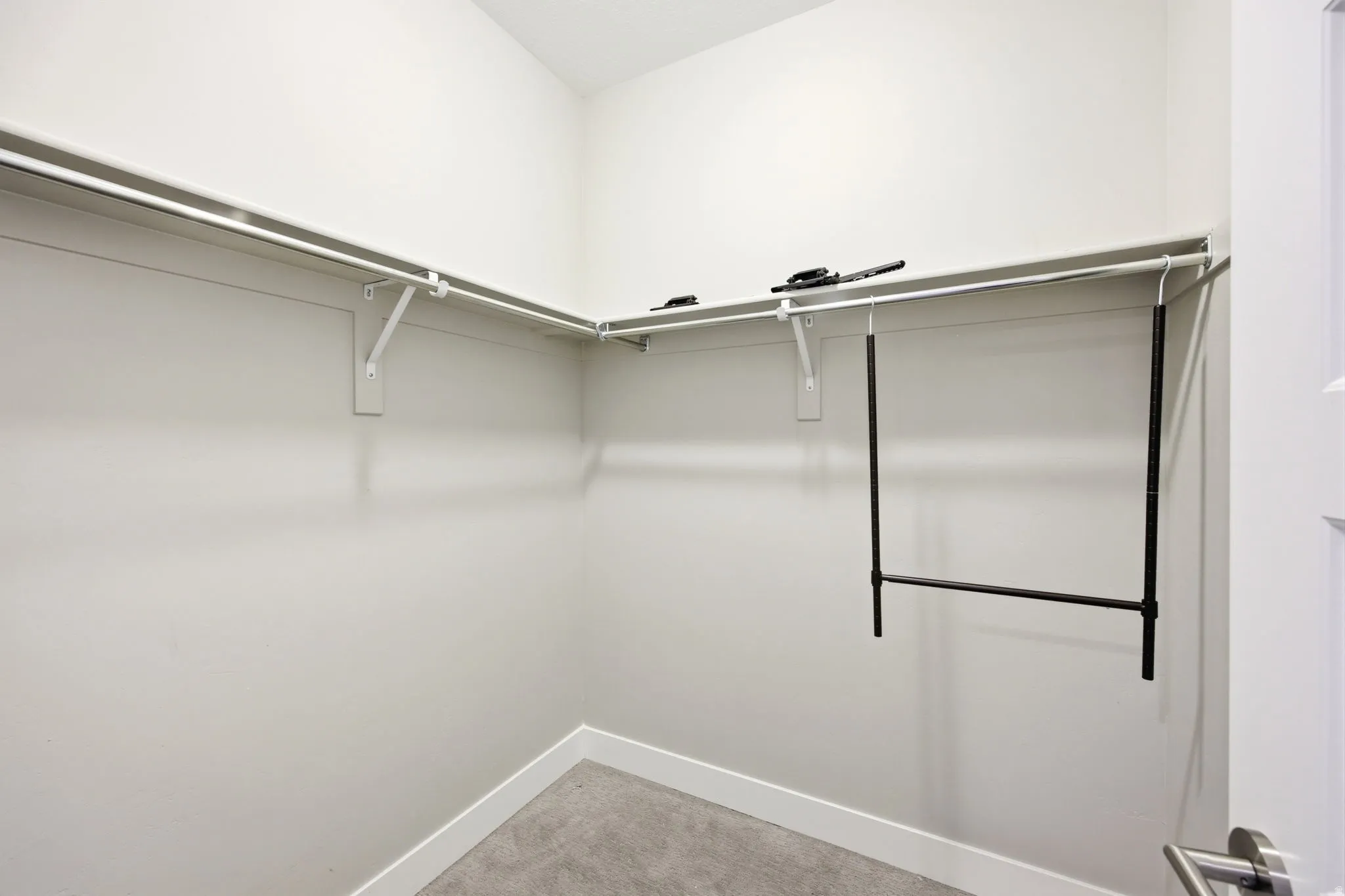 Walk-in closet featuring white walls, white shelving, and a built-in hanging rod system