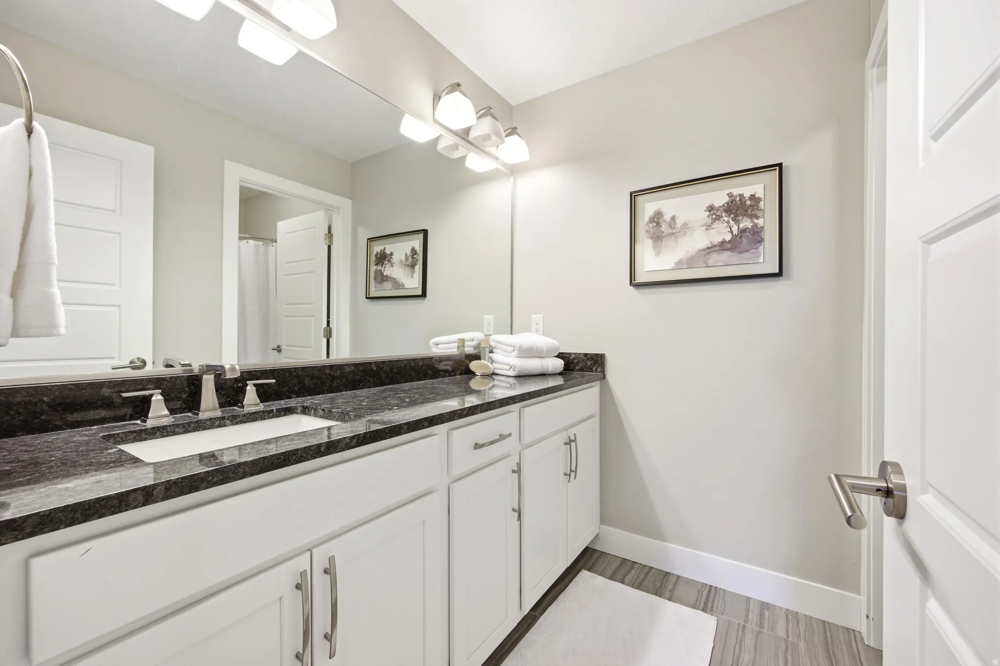 Bathroom vanity featuring a dark stone countertop with an integrated rectangular sink