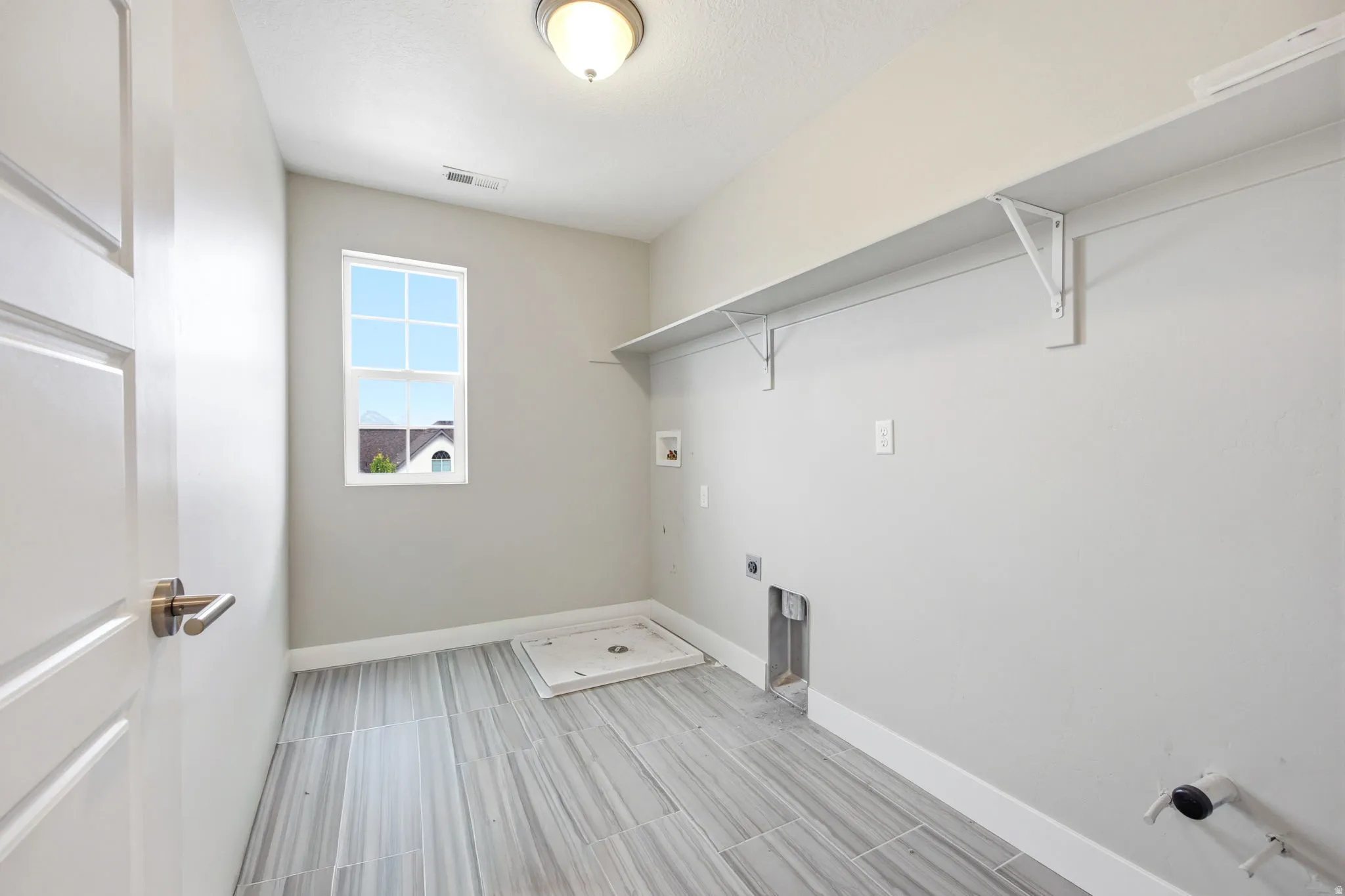 Utility room featuring wood-finish tile flooring, a window, overhead lighting, and wall-mounted shelving