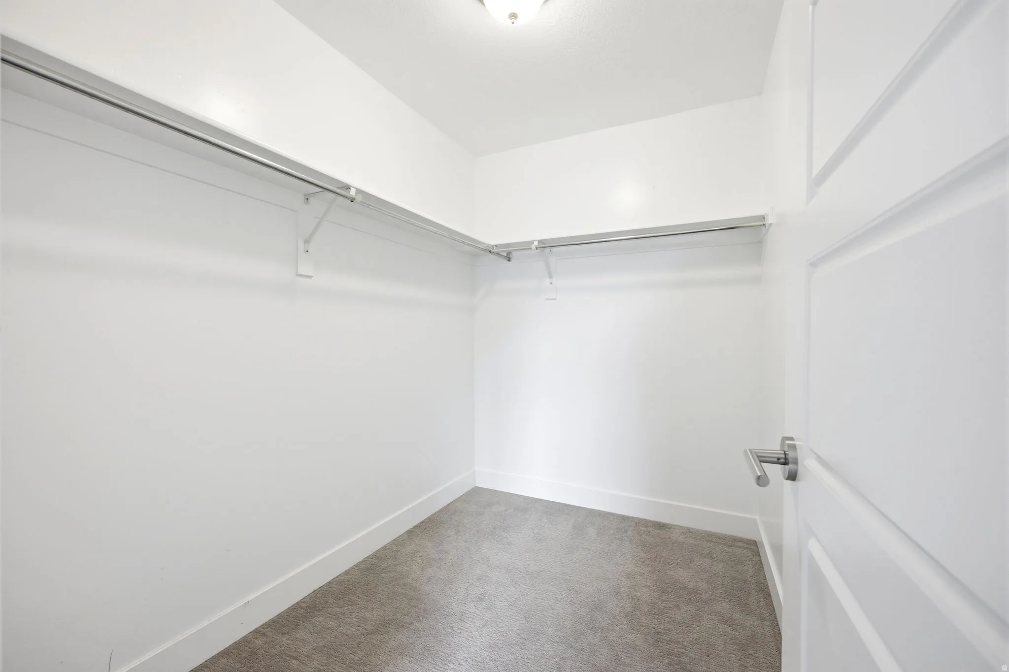 Walk-in closet featuring plush gray carpeting, white walls, and a recessed ceiling light