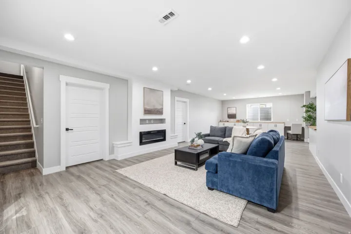 Spacious lower-level living area featuring wood-finish flooring, recessed lighting, and a built-in electric fireplace