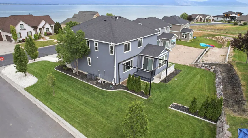 Expansive green lawn surrounds this two-story residence with dark grey siding and a black shingle roof