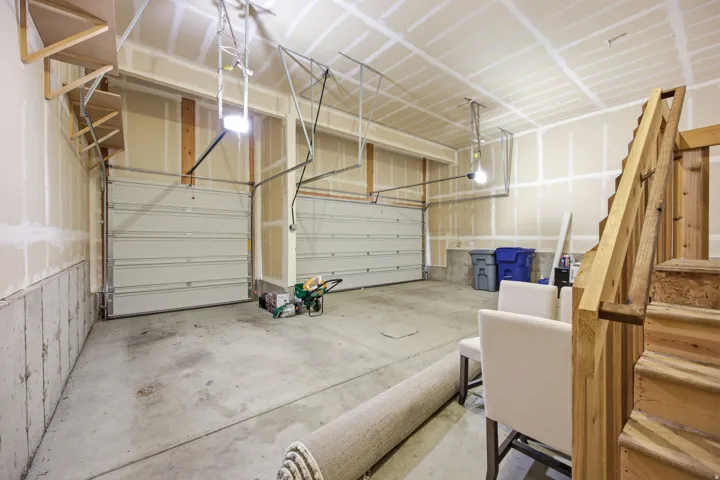 Spacious garage featuring two overhead doors, concrete flooring, and bare drywall walls