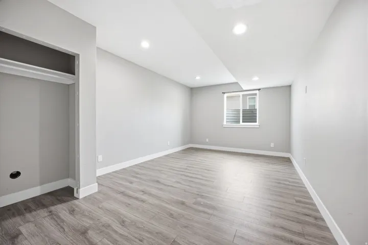 Spacious room featuring wood-finish flooring, recessed lighting, and a neutral wall palette