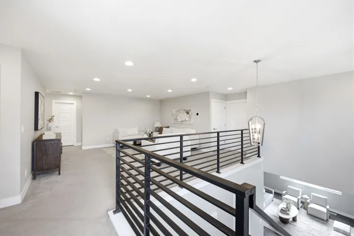 Upper-level loft area with carpet flooring and recessed lighting