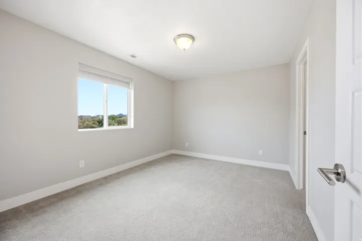 Bright room featuring a window with white blinds, neutral carpeting, light-toned walls, and a flush-mount ceiling light