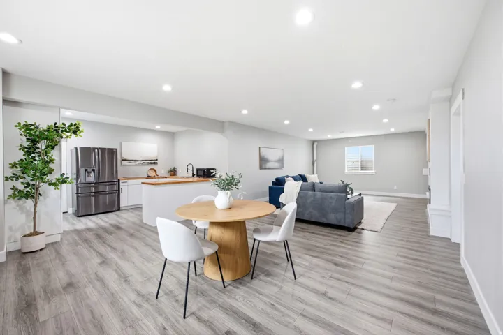 Open-concept living area featuring wood-finish flooring, recessed lighting, a modern kitchen with white cabinetry, a kitchen island with a wood countertop, and stainless steel appliances
