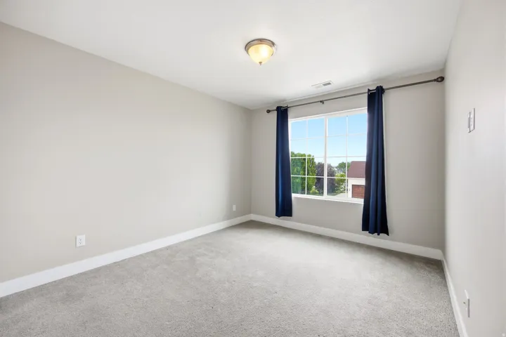 Carpeted room featuring a large window with white muntins, light gray painted walls, white baseboards, and a semi-flush mount ceiling light
