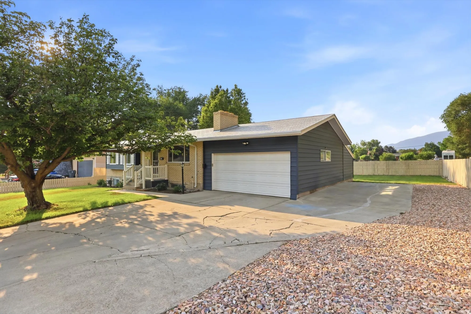 Exterior featuring a large driveway, attached garage, and a manicured front lawn