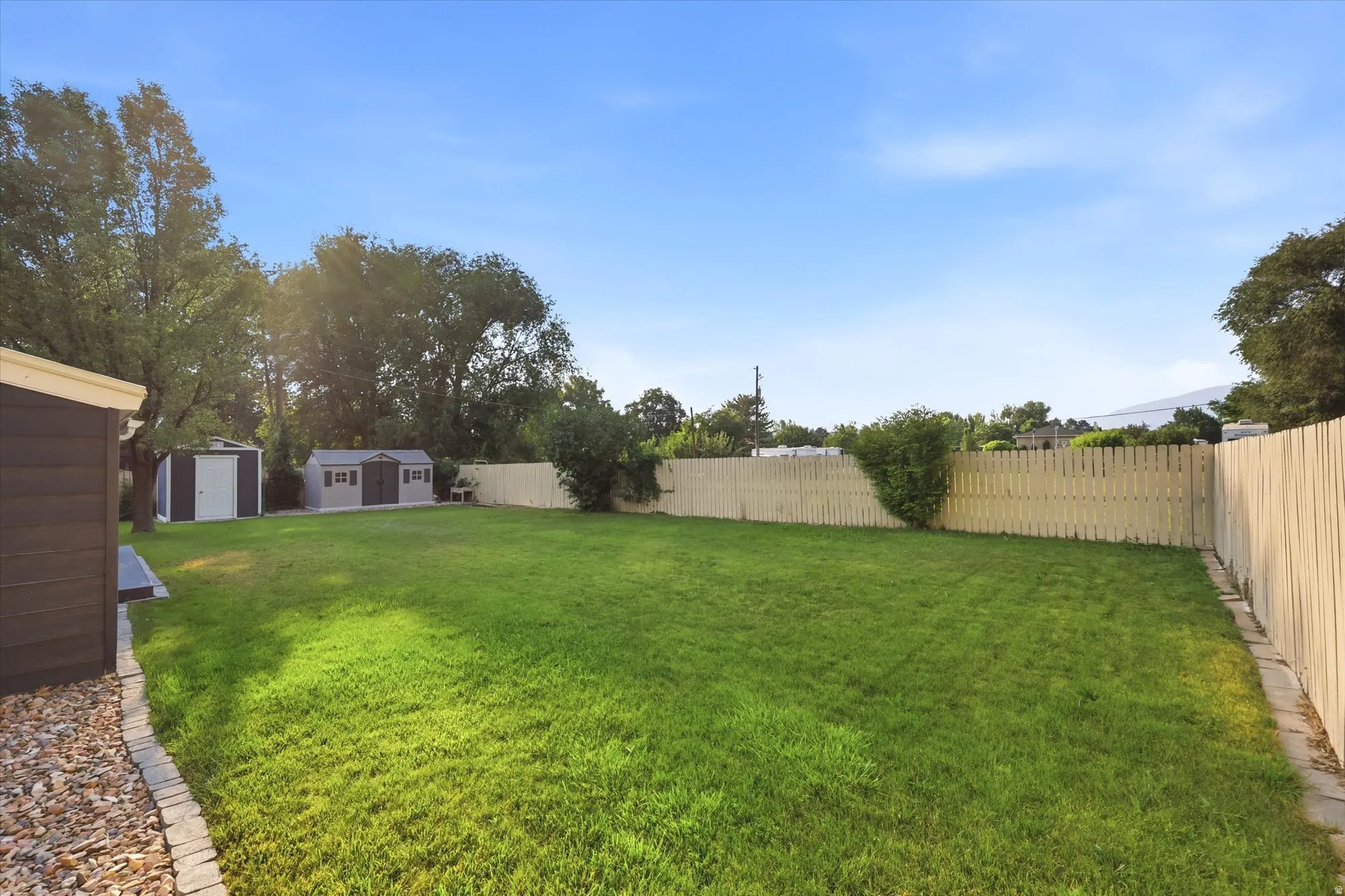 Spacious green lawn surrounded by a light-toned wood fence