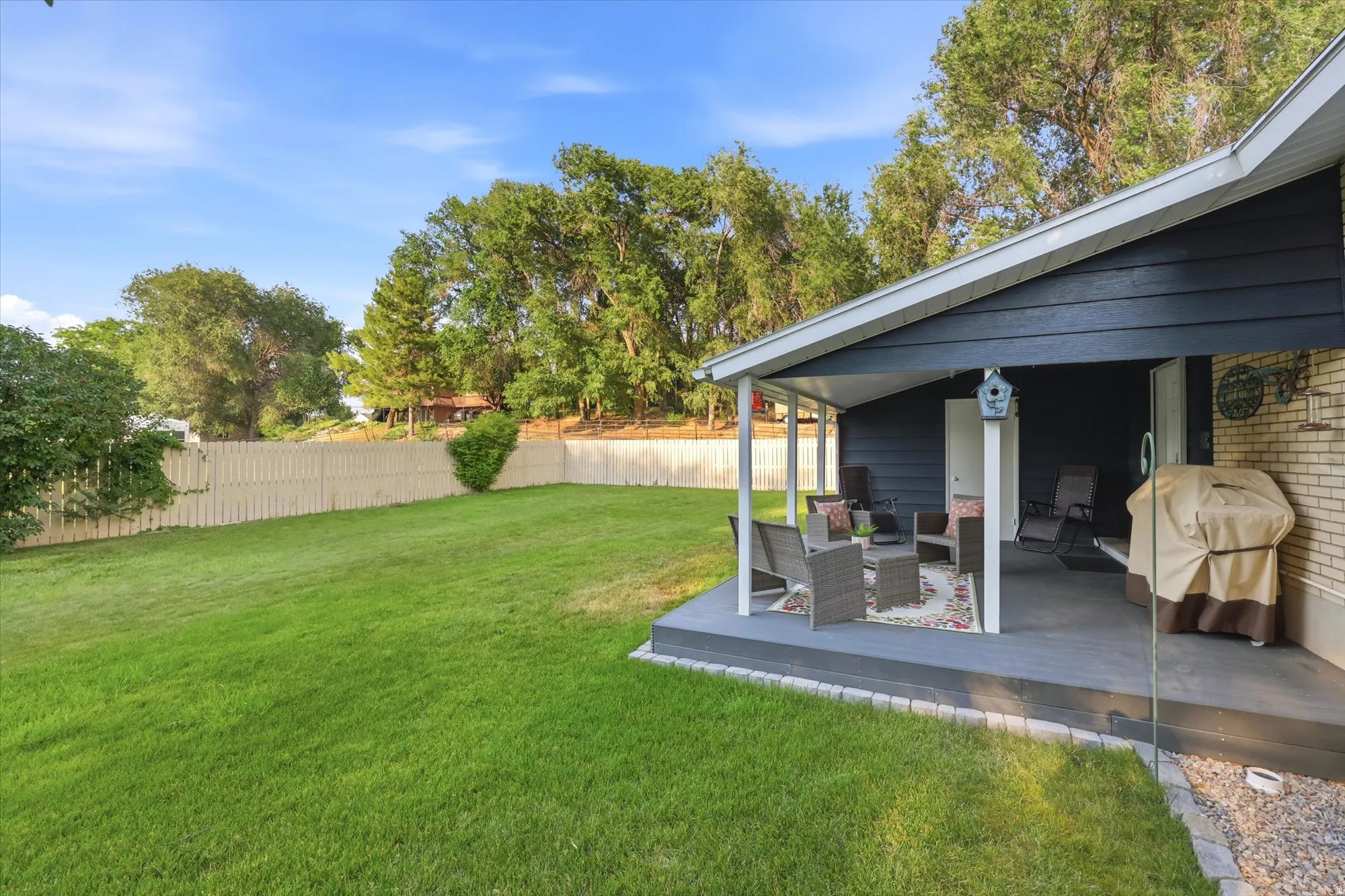 Expansive grassy yard with a light-toned privacy fence