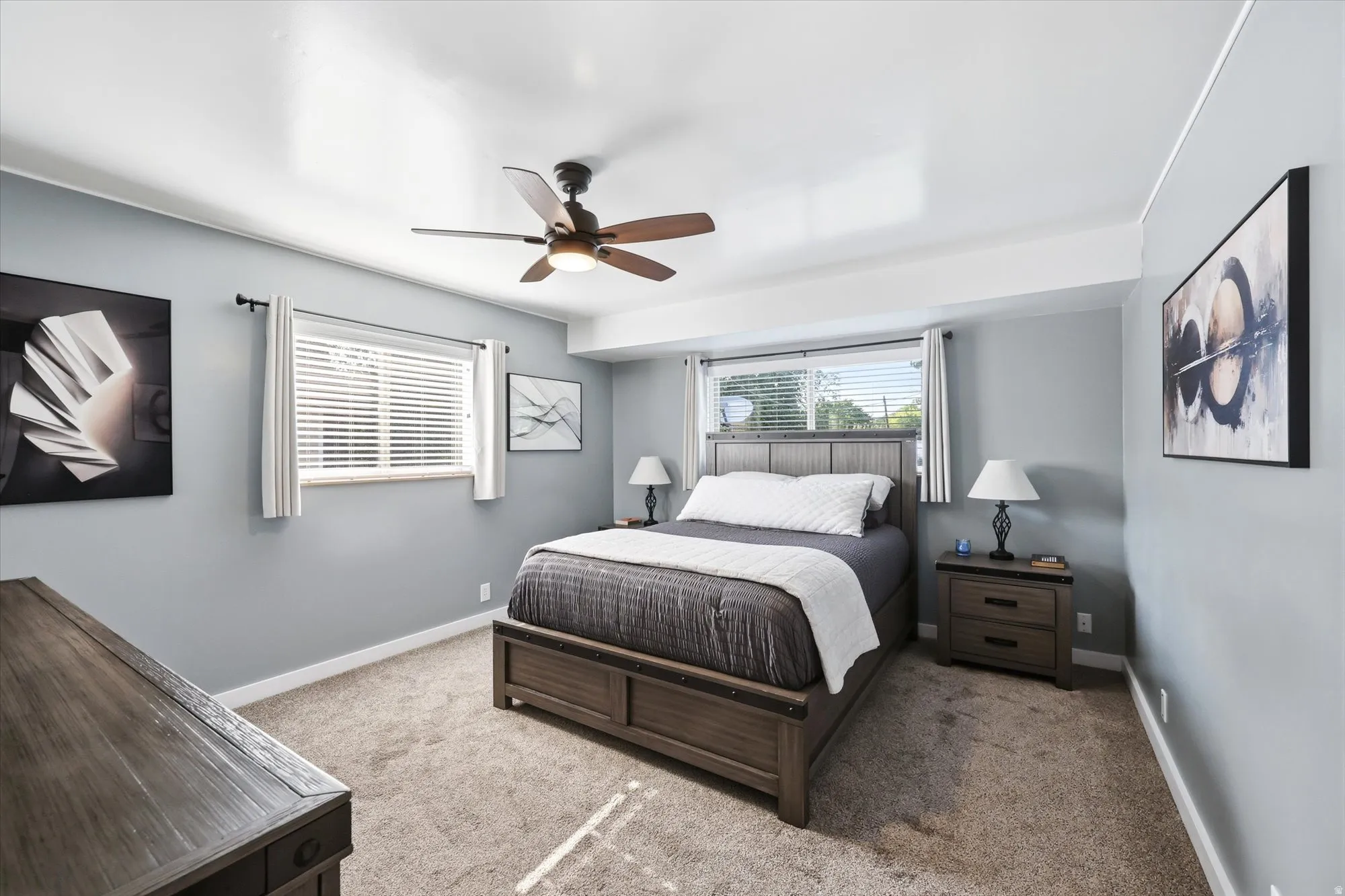Carpeted bedroom featuring a ceiling fan with integrated lighting, a window with blinds, and light gray wall paint