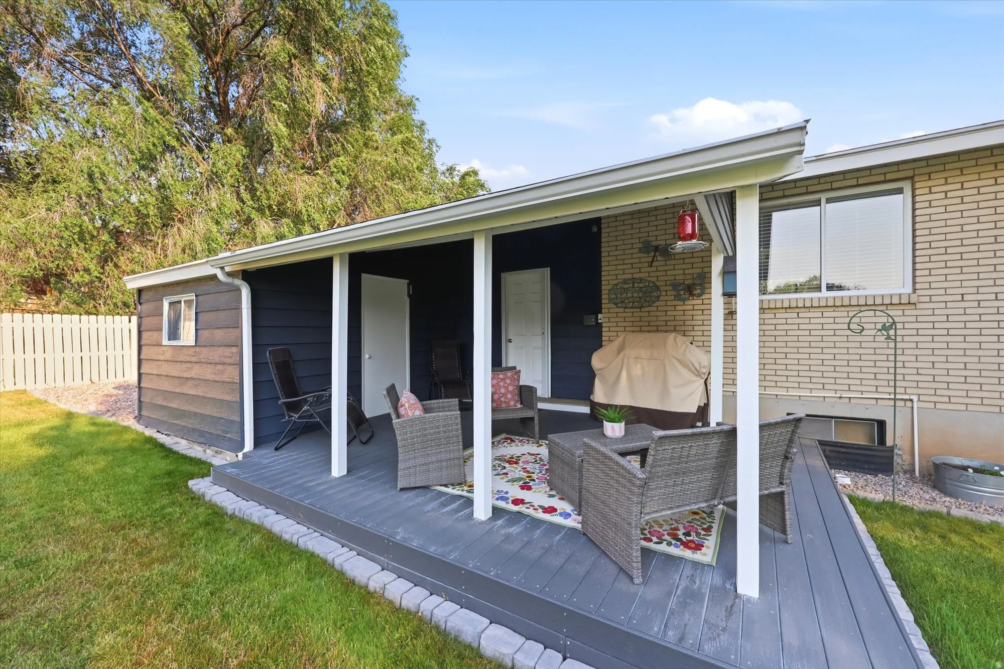 Covered patio featuring a solid roof, white support posts, and dark gray decking