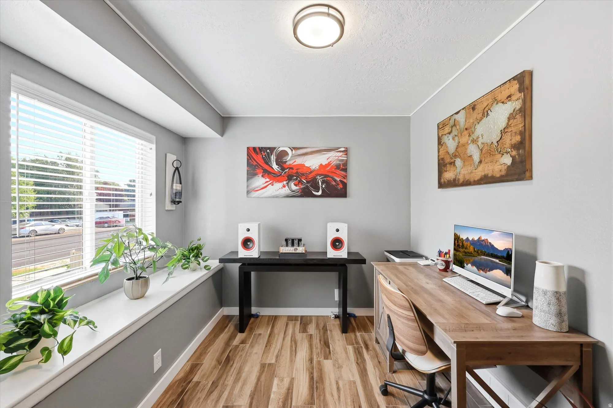Dedicated office space featuring wood-finish flooring, a large window with blinds, and light gray painted walls