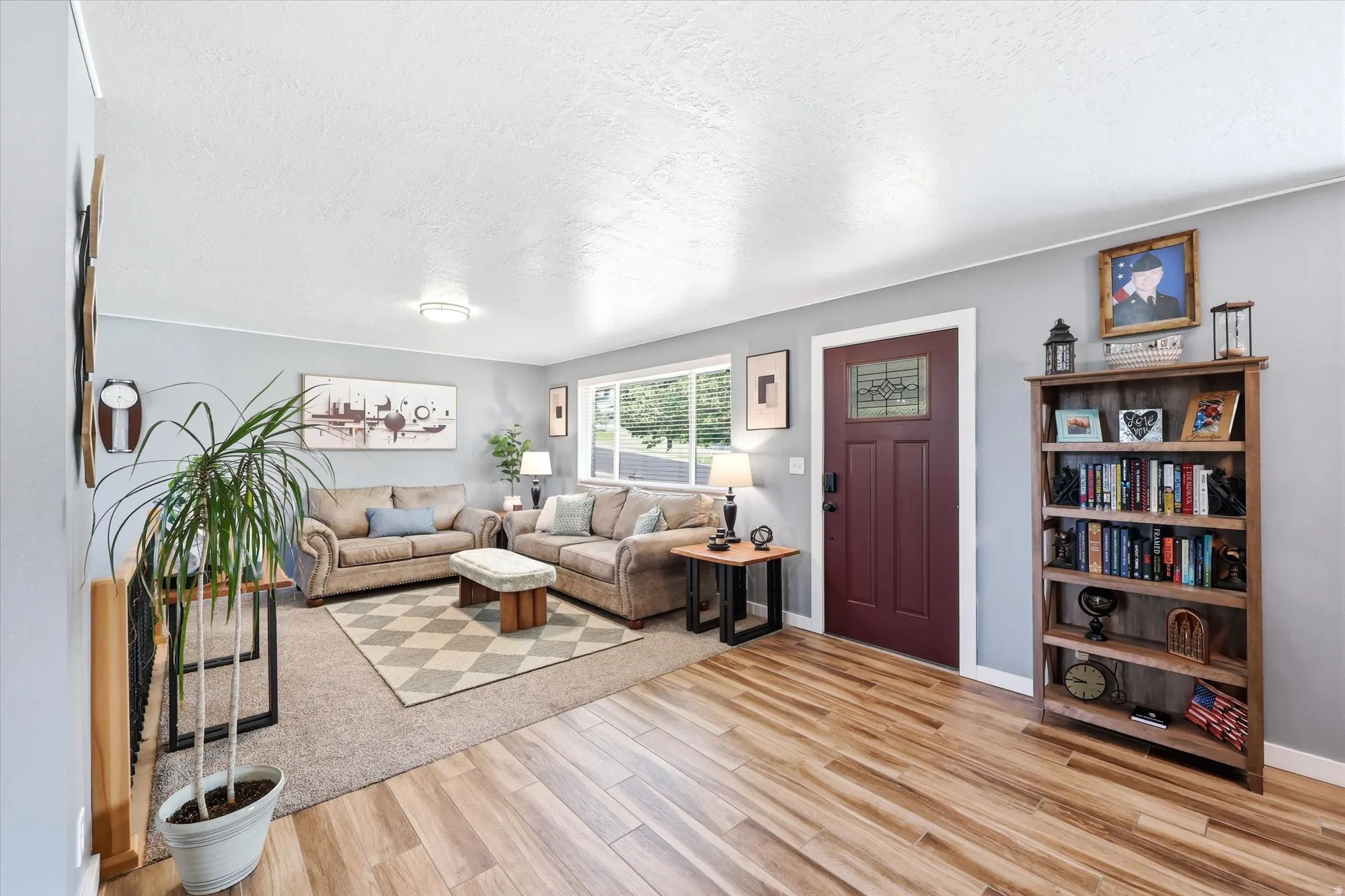 Living area featuring wood-finish flooring, a burgundy entry door with decorative glass, and light gray wall paint