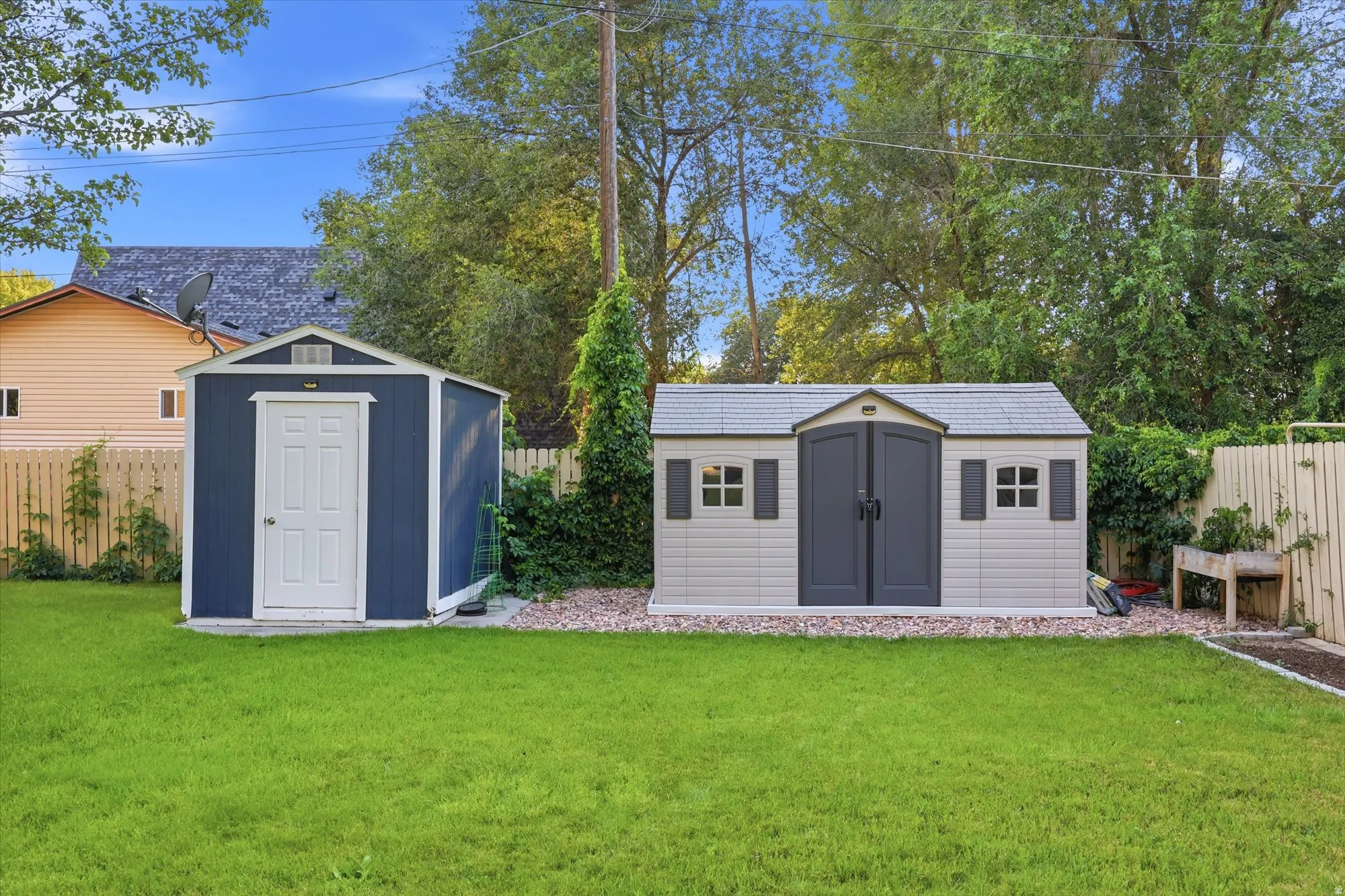 Expansive green lawn with two detached storage sheds