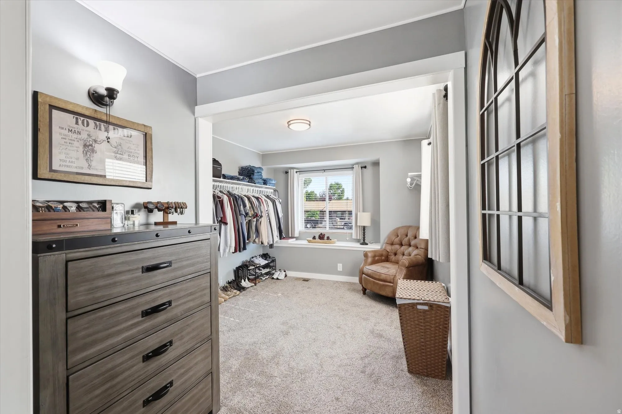 Spacious walk-in closet with carpet flooring, built-in clothing racks, and a window seat with natural light