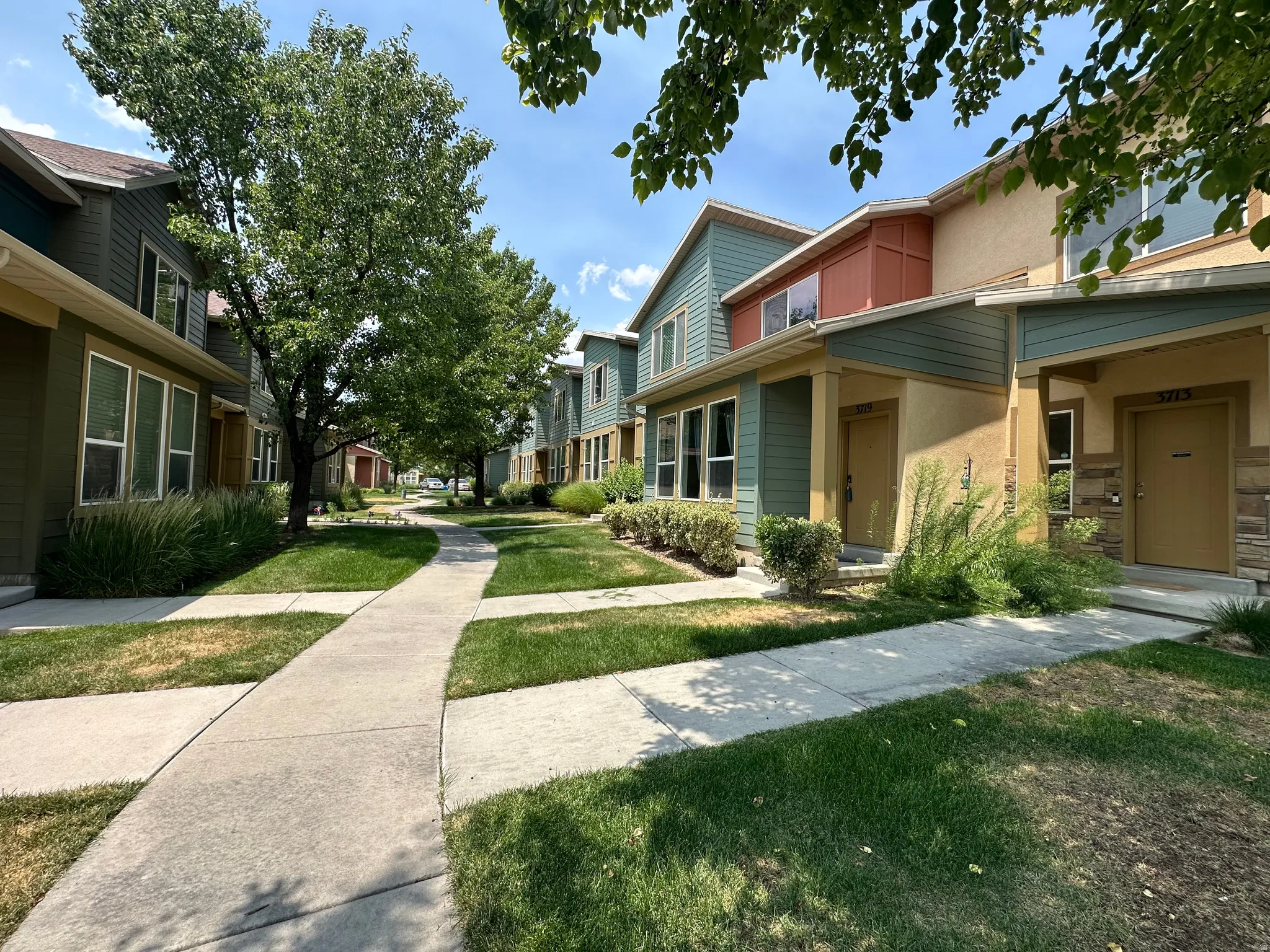 Row of multi-story residences featuring varied siding materials including board and batten, stucco, and stone veneer accents
